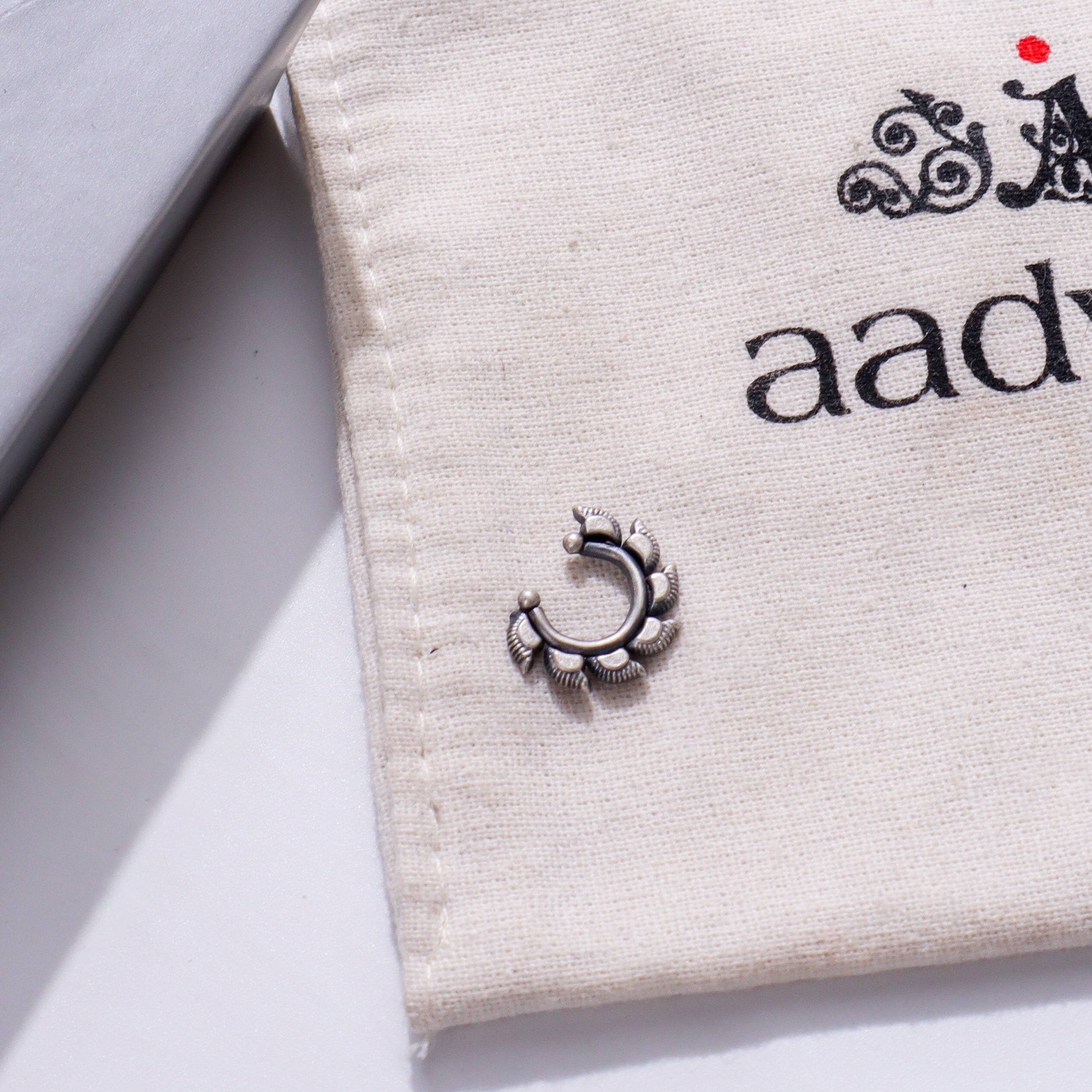 Sterling silver septum nose ring on beige jewelry pouch