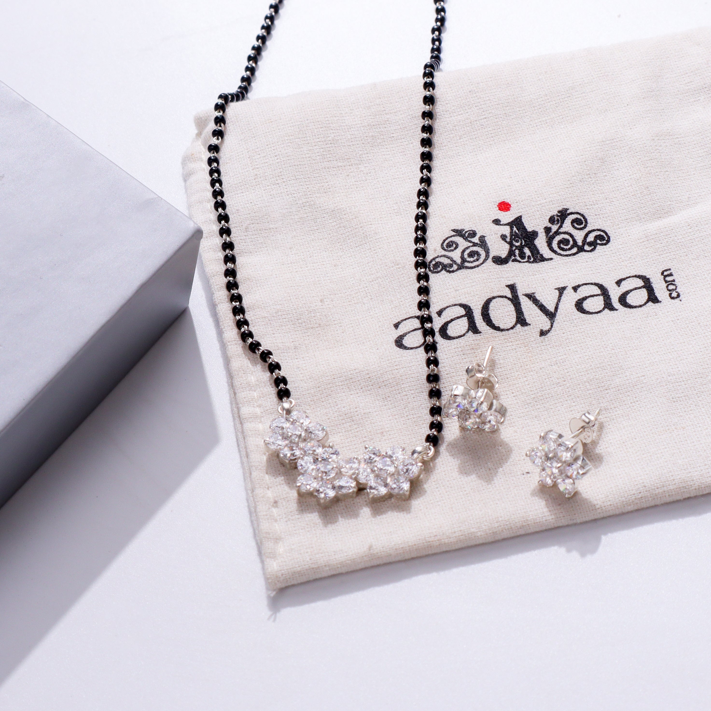 Black beaded necklace with crystal flower pendant on beige fabric