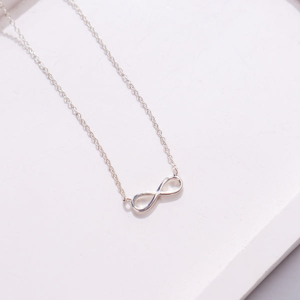 Silver infinity pendant necklace on white background