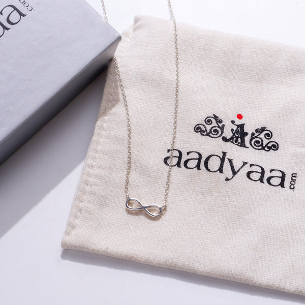Silver infinity pendant necklace on beige fabric with jewelry box
