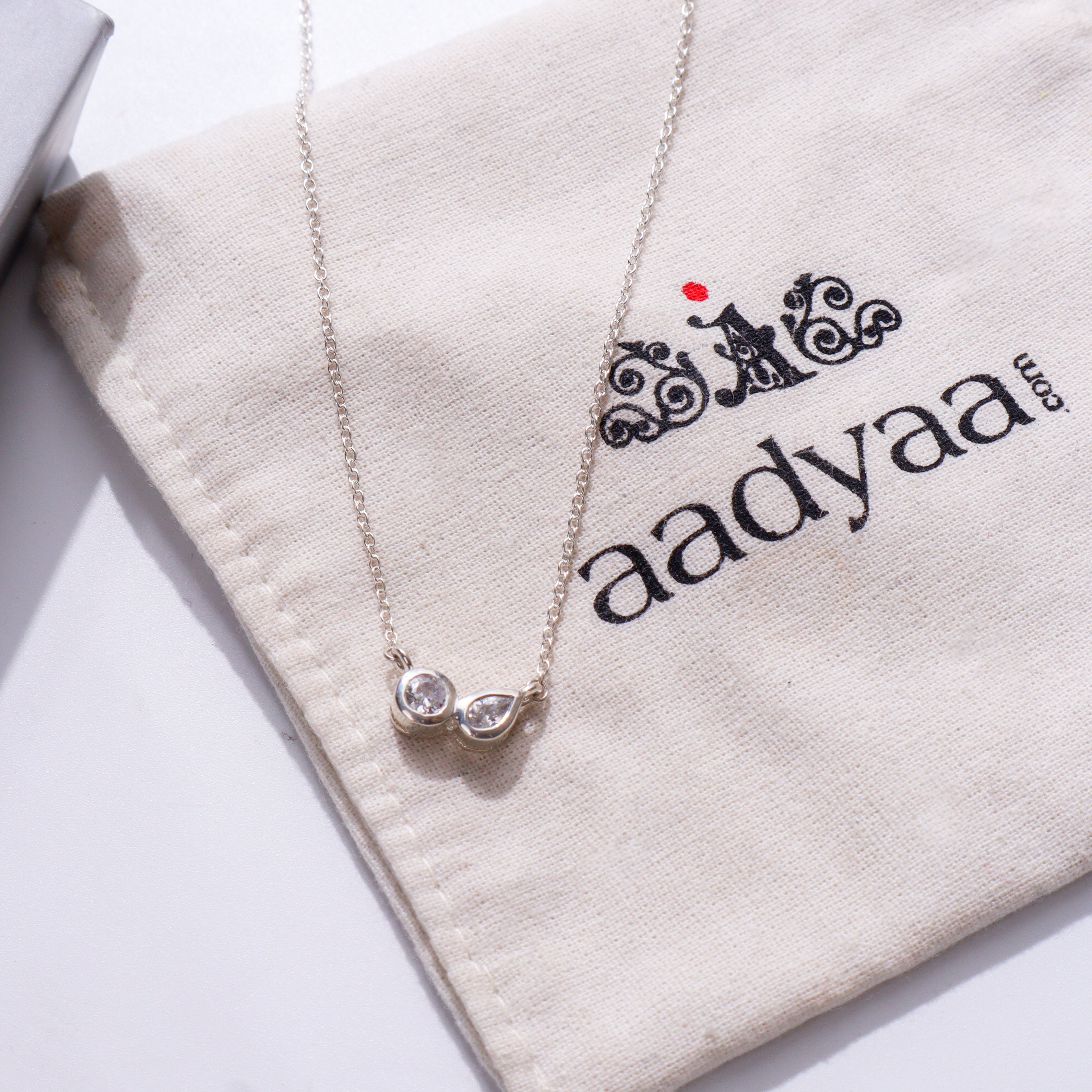 Silver chain with twin CZ dots on beige fabric