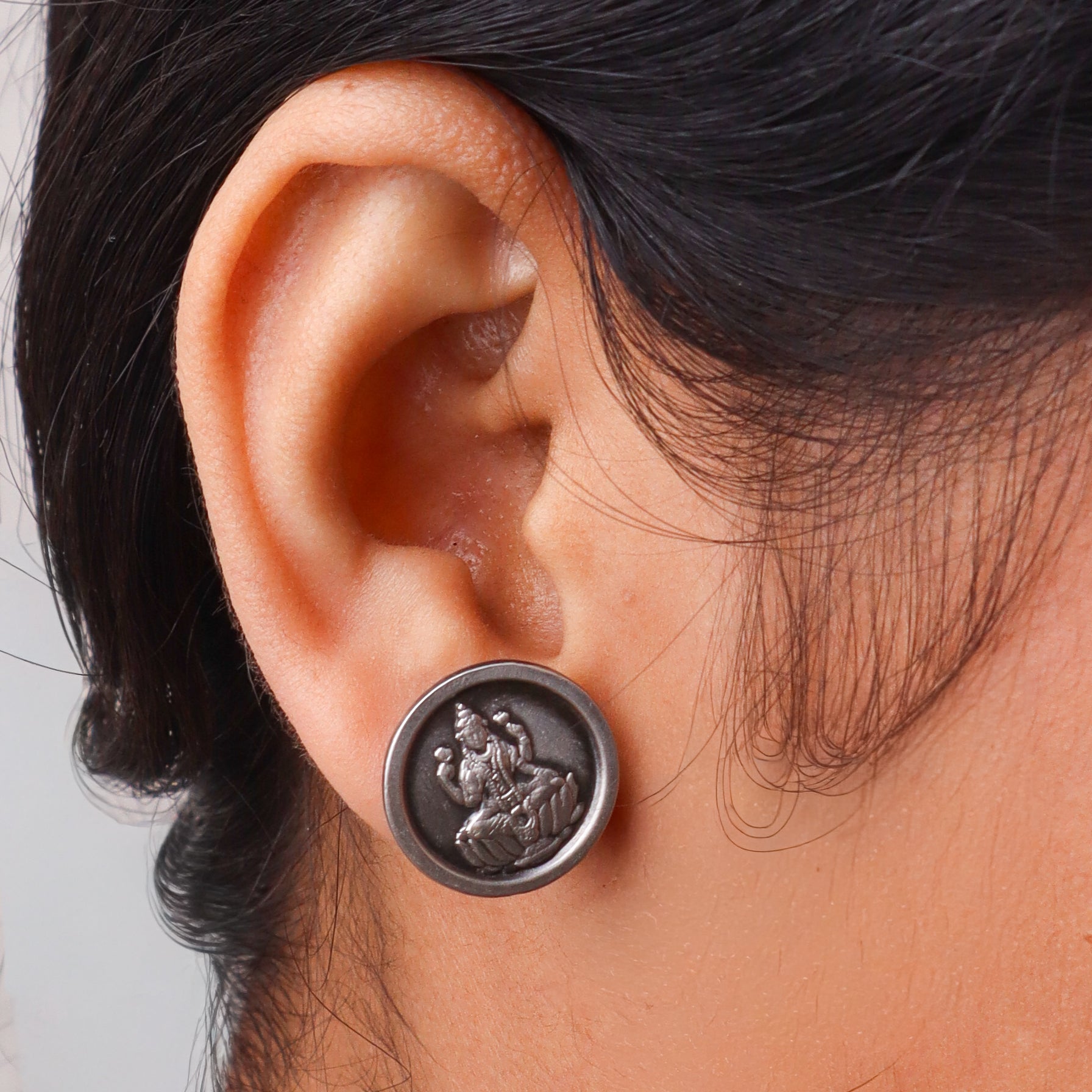 Close-up of goddess Lakshmi embossed silver earrings