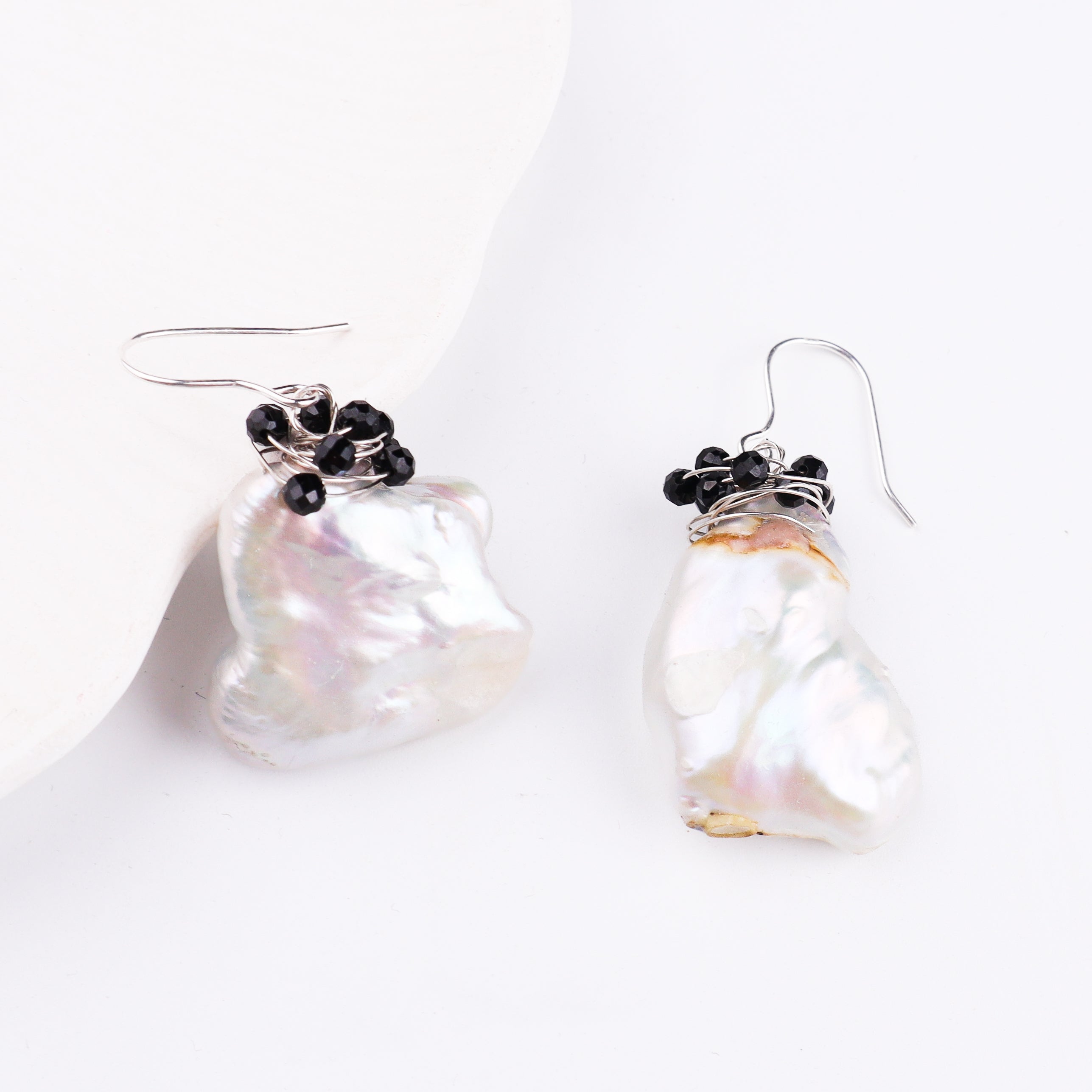 Pearl and black bead earrings on white surface