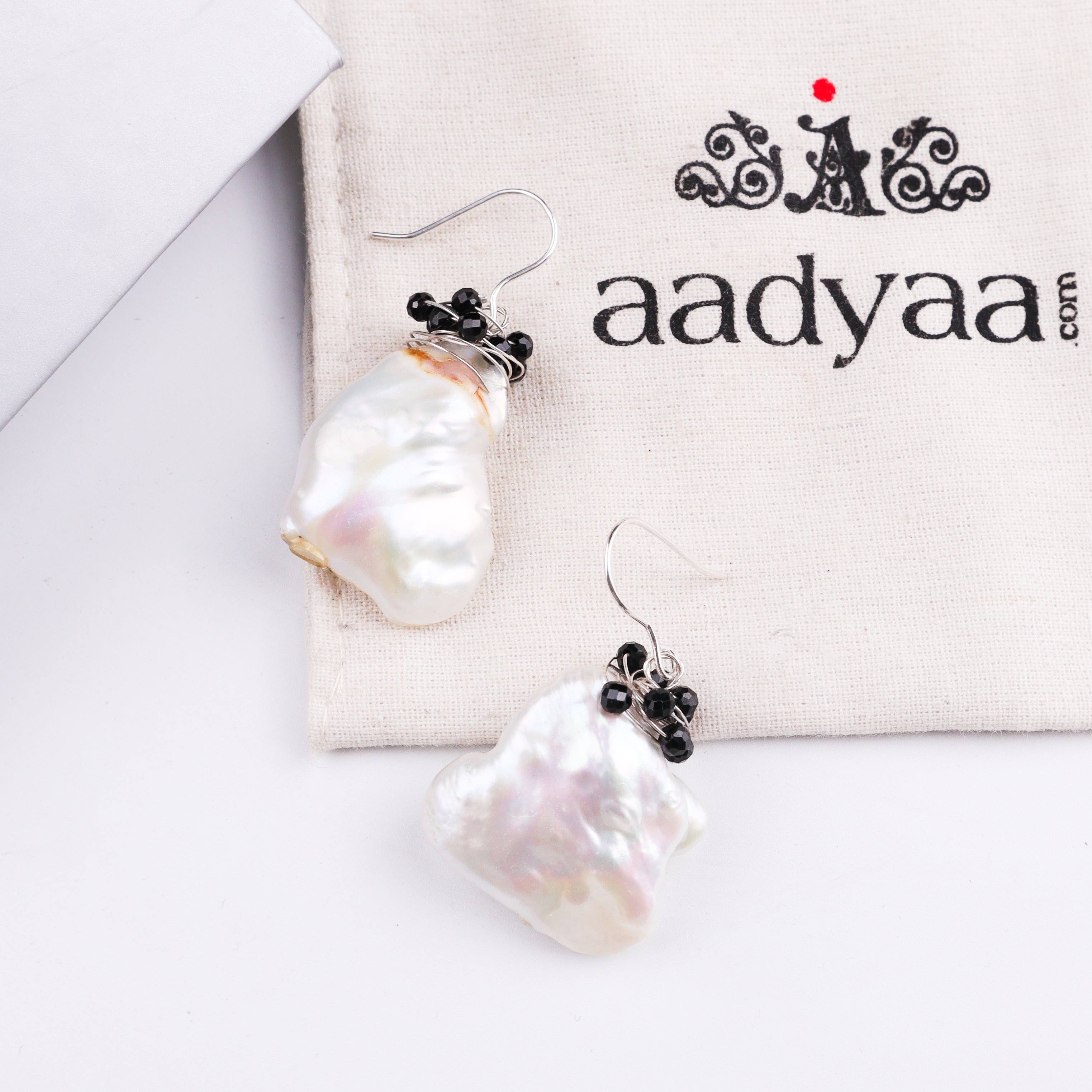 Earrings with black beads and pearl on white fabric pouch
