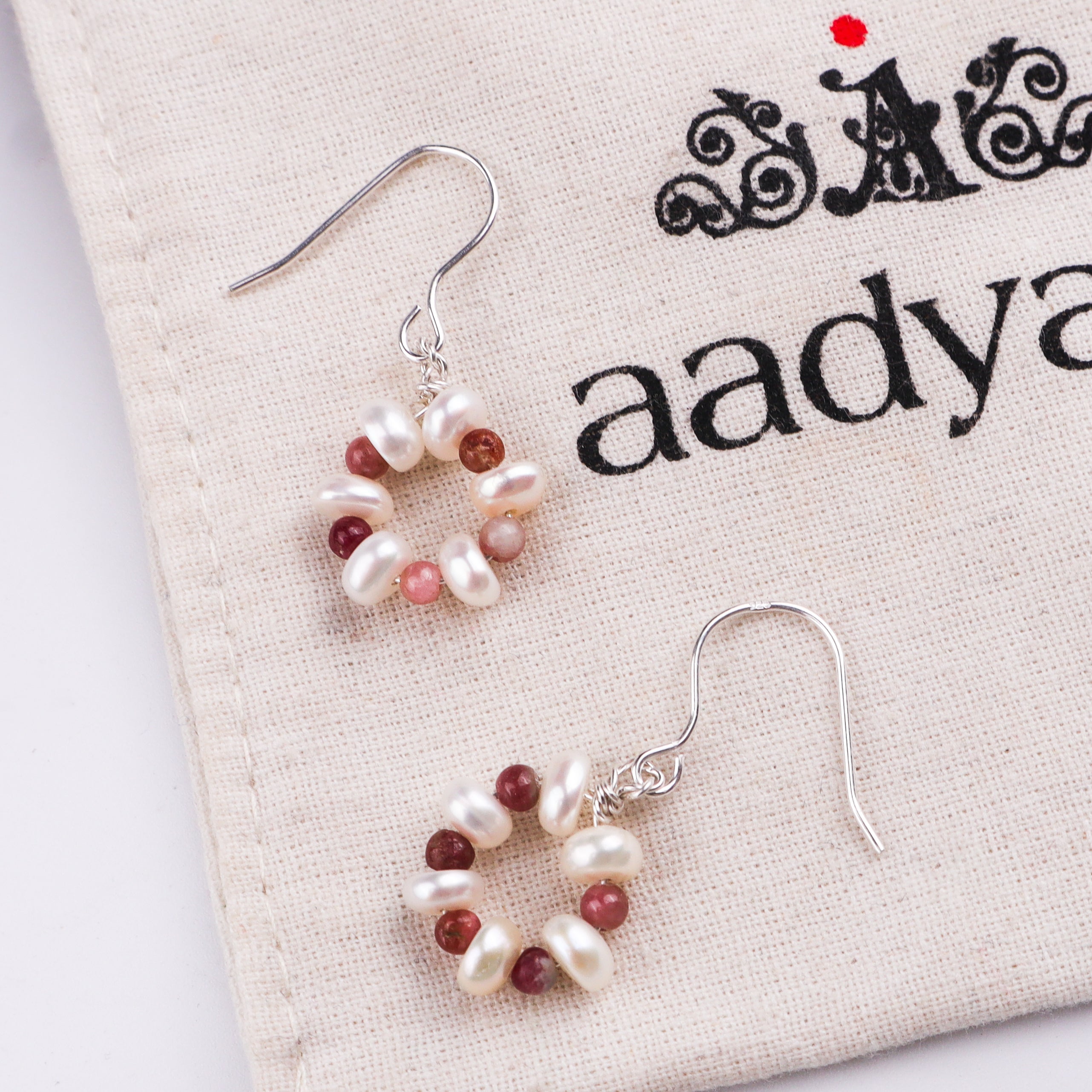 Pearl and red gemstone earrings on fabric with text