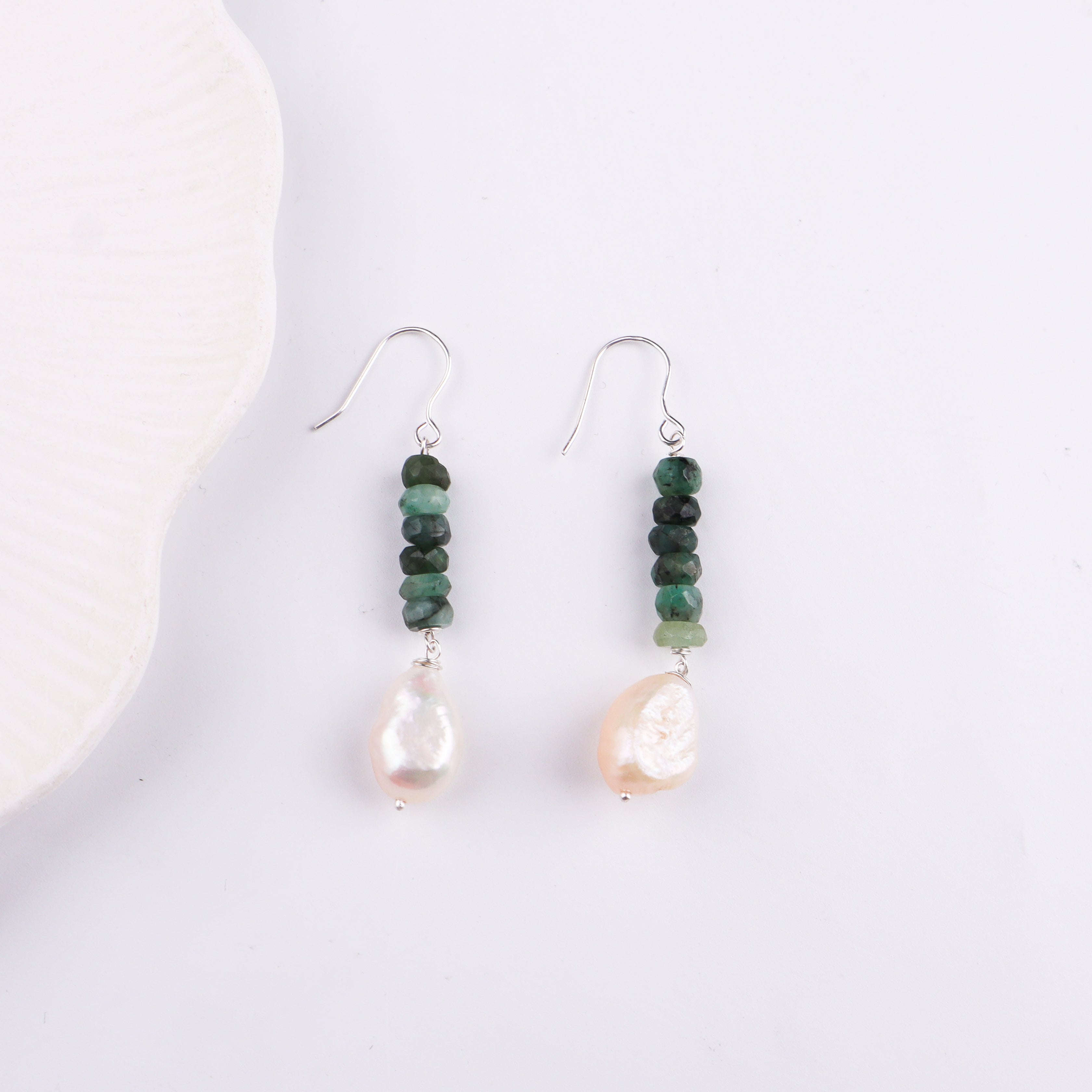 Silver hook earrings with green beads and pearl drops on white surface