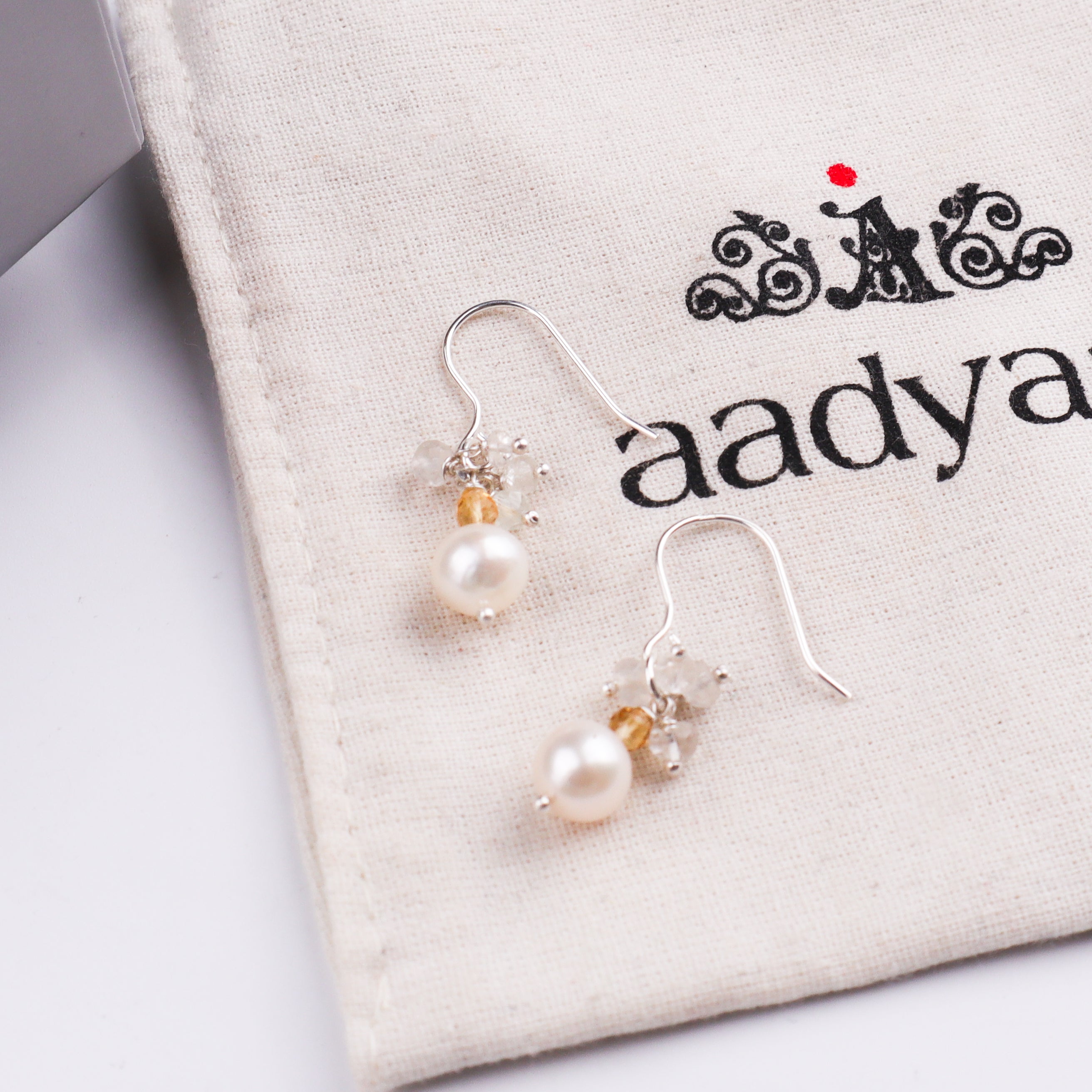 Pearl and crystal earrings on white textured surface