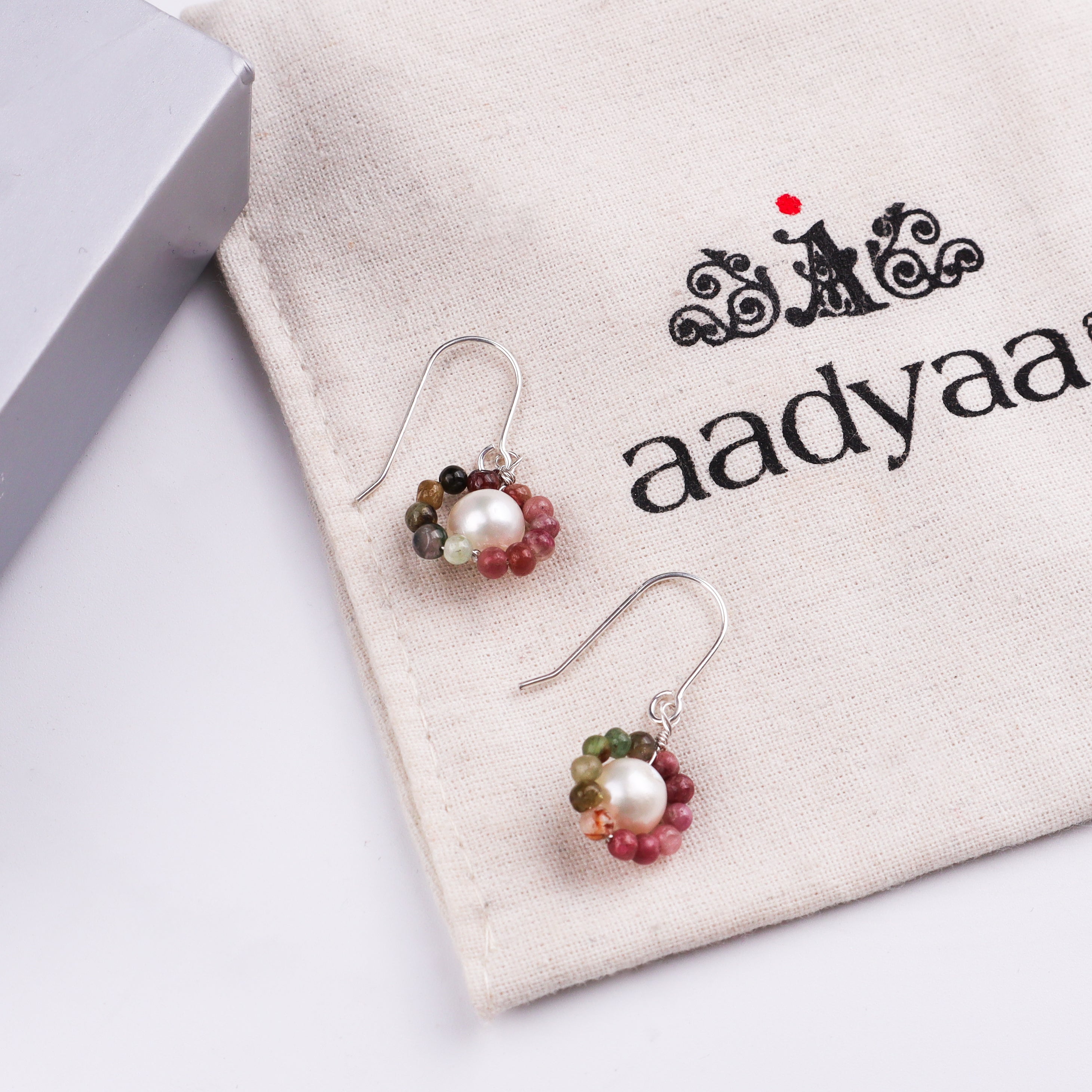 Beaded pearl and silver earrings on white background