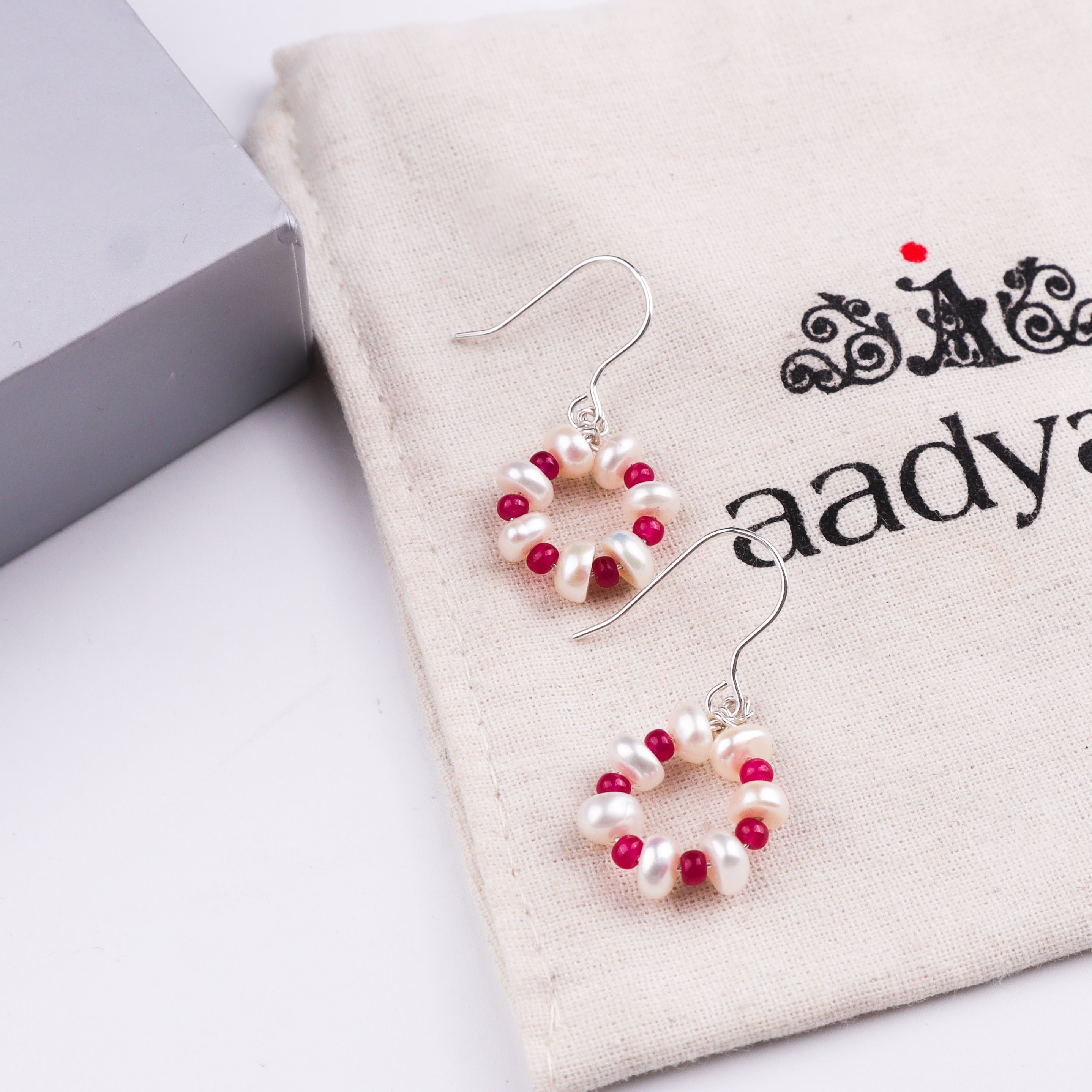 Close-up of pearl and ruby earrings on white background