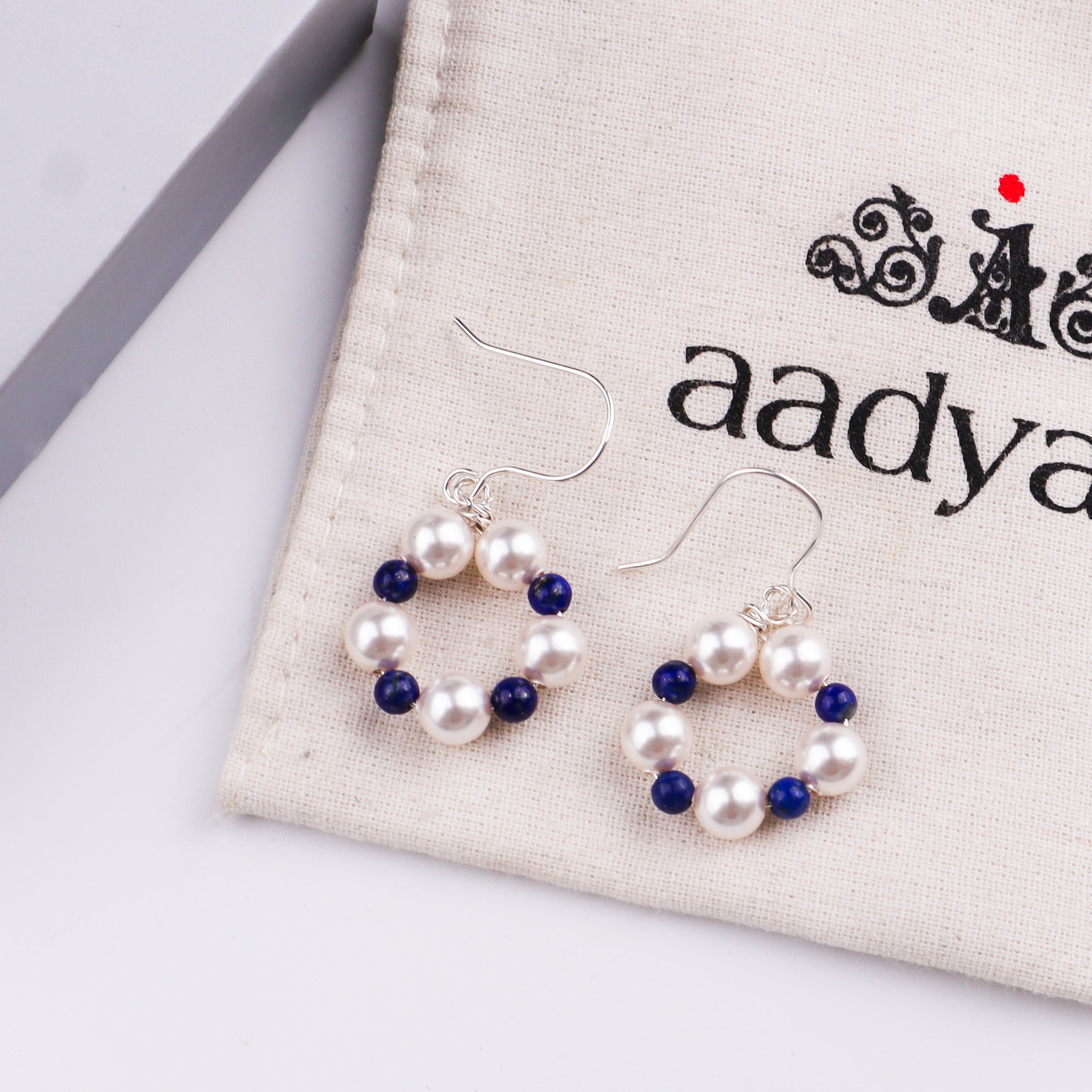 Pearl and lapis lazuli beaded earrings displayed on fabric pouch