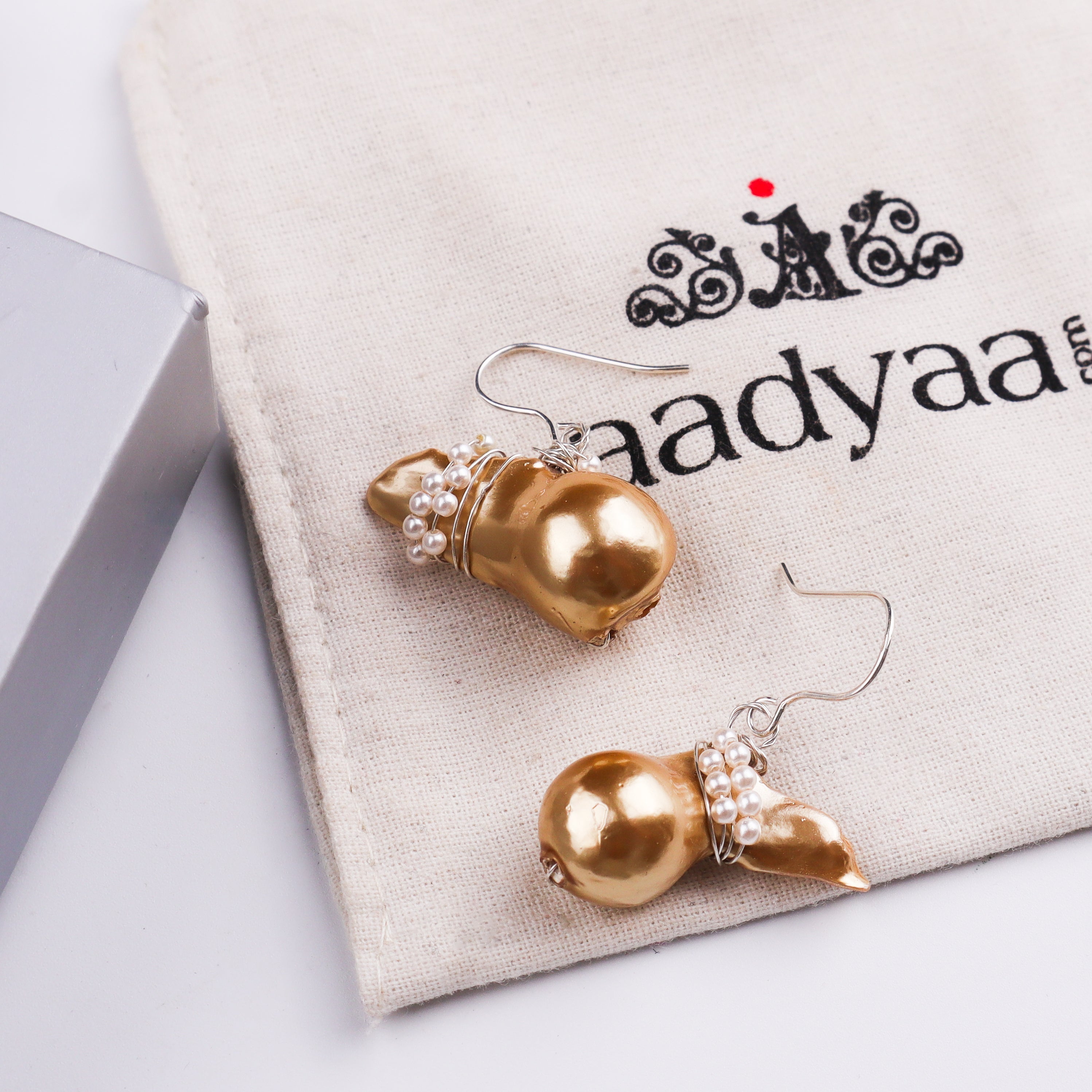 Pearl and gold earrings displayed on white fabric