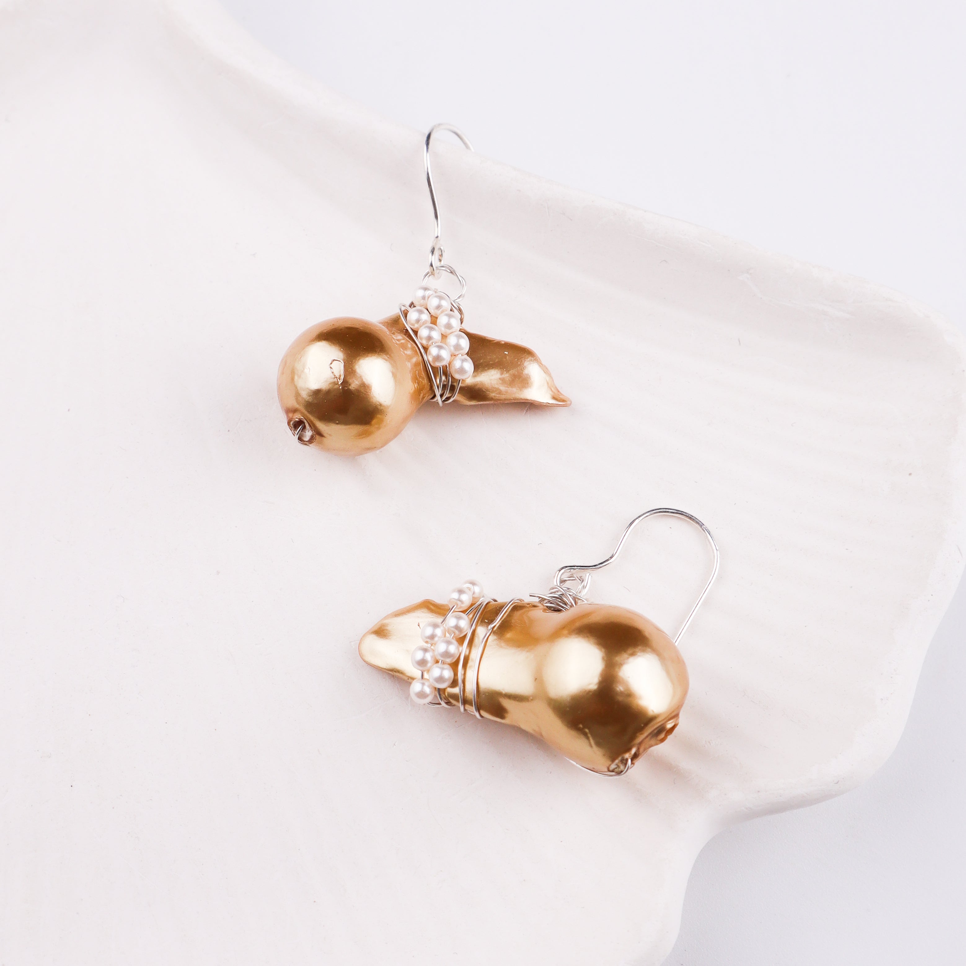 Elegant pearl and gold earrings on white surface