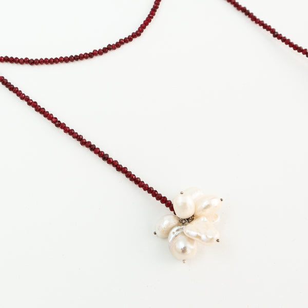 Detailed view of garnet beaded necklace with pearl cluster pendant