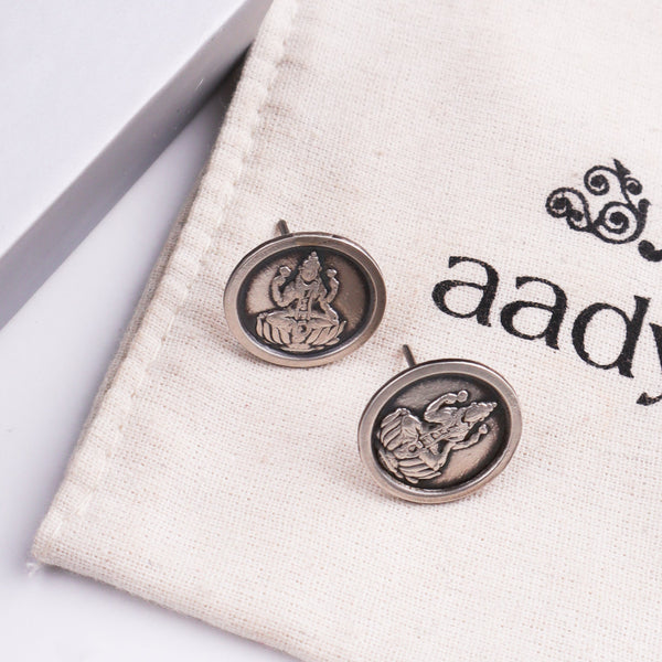 Silver earrings with goddess Lakshmi motif on fabric background