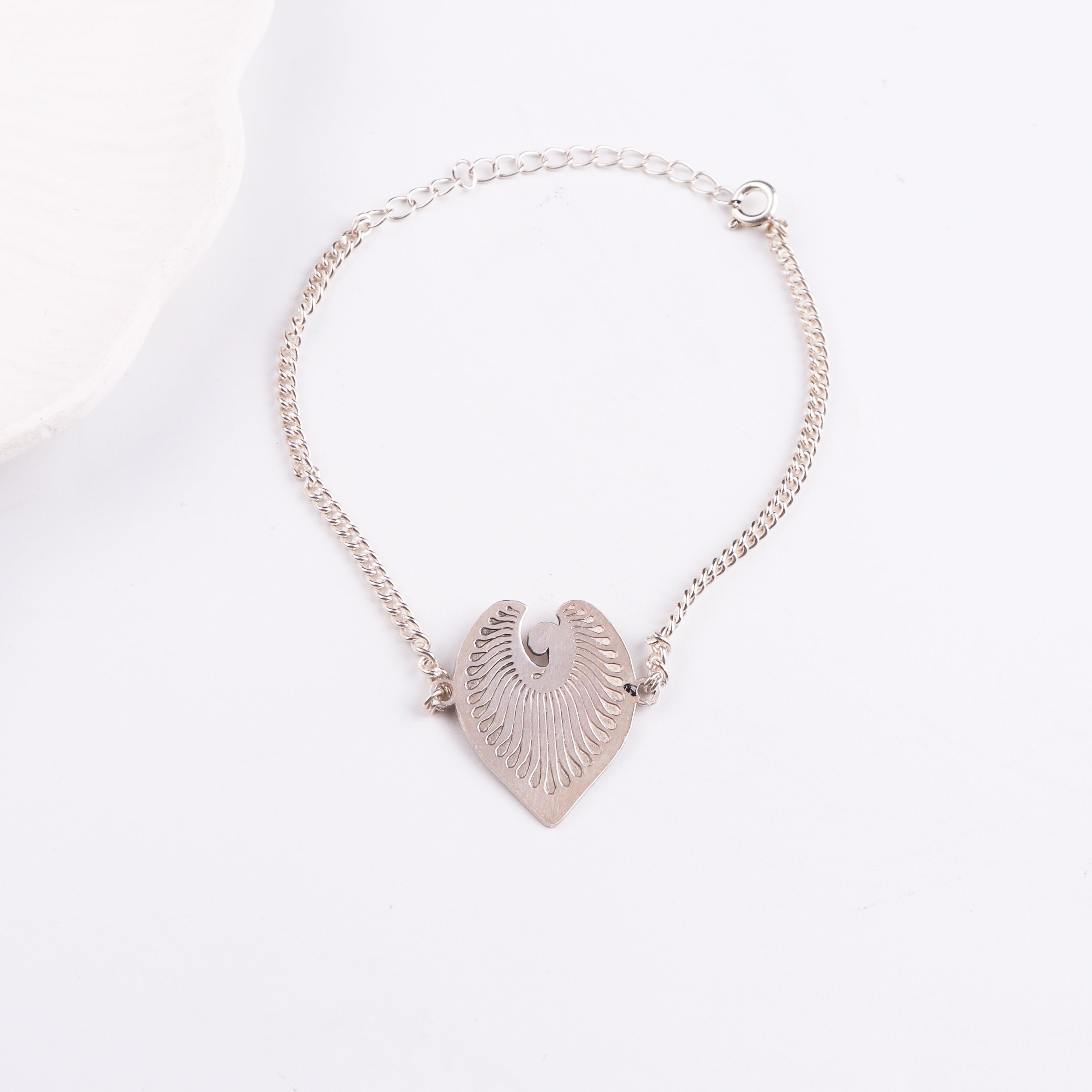Silver chain bracelet with leaf pendant on white background