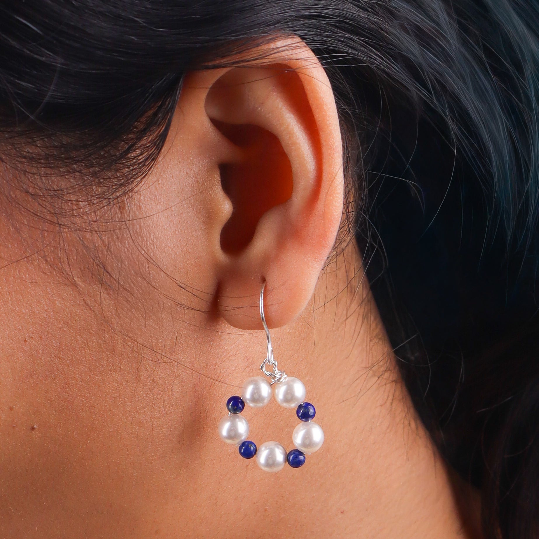 Close-up of pearl and lapis lazuli earrings on white background