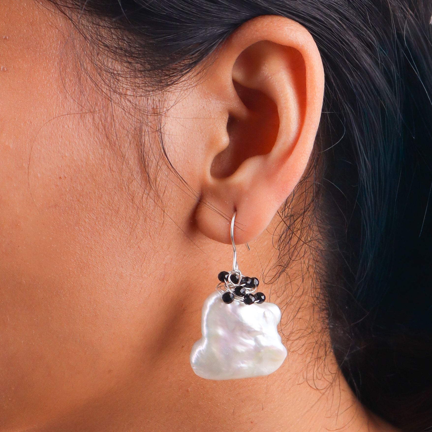 Close-up of pearl and black spinel earrings on white background
