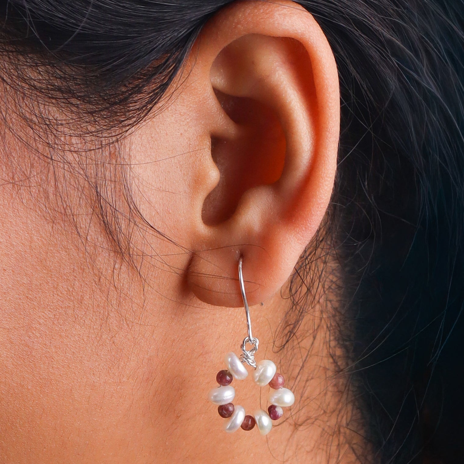 Close-up of pearl and red gemstone earrings on white background