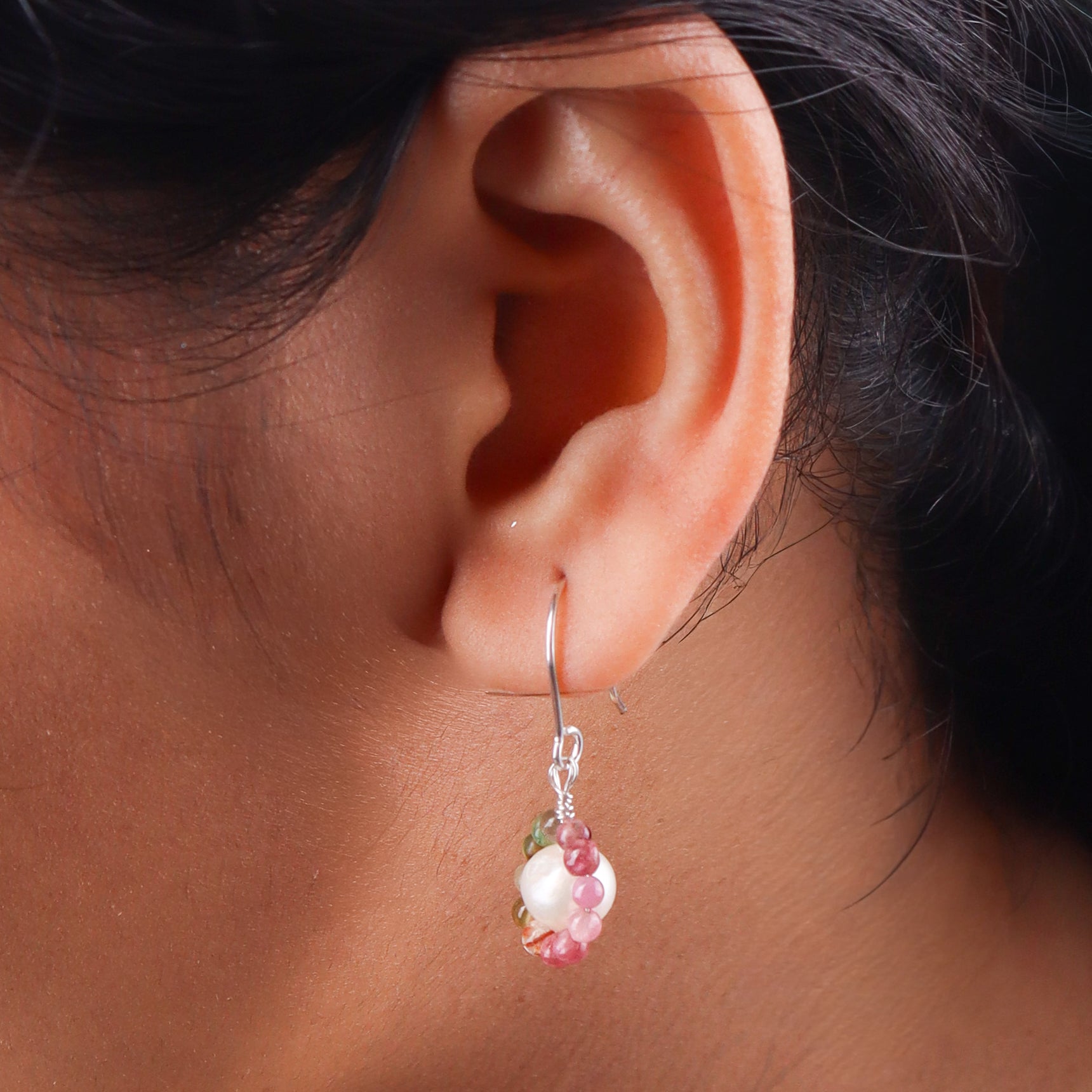 Close-up of silver earring with pearl and beads