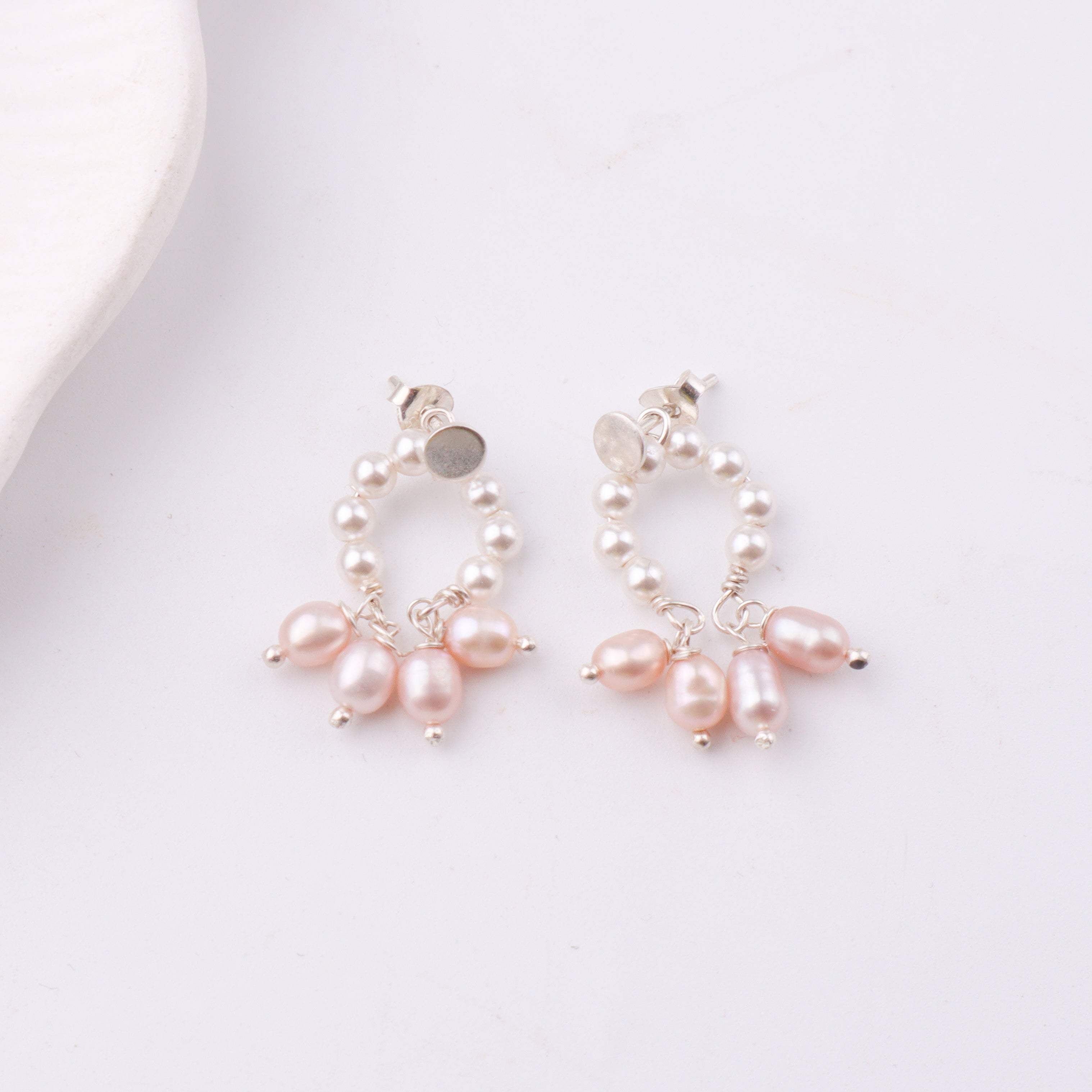 Pearl earrings with silver backing on white background