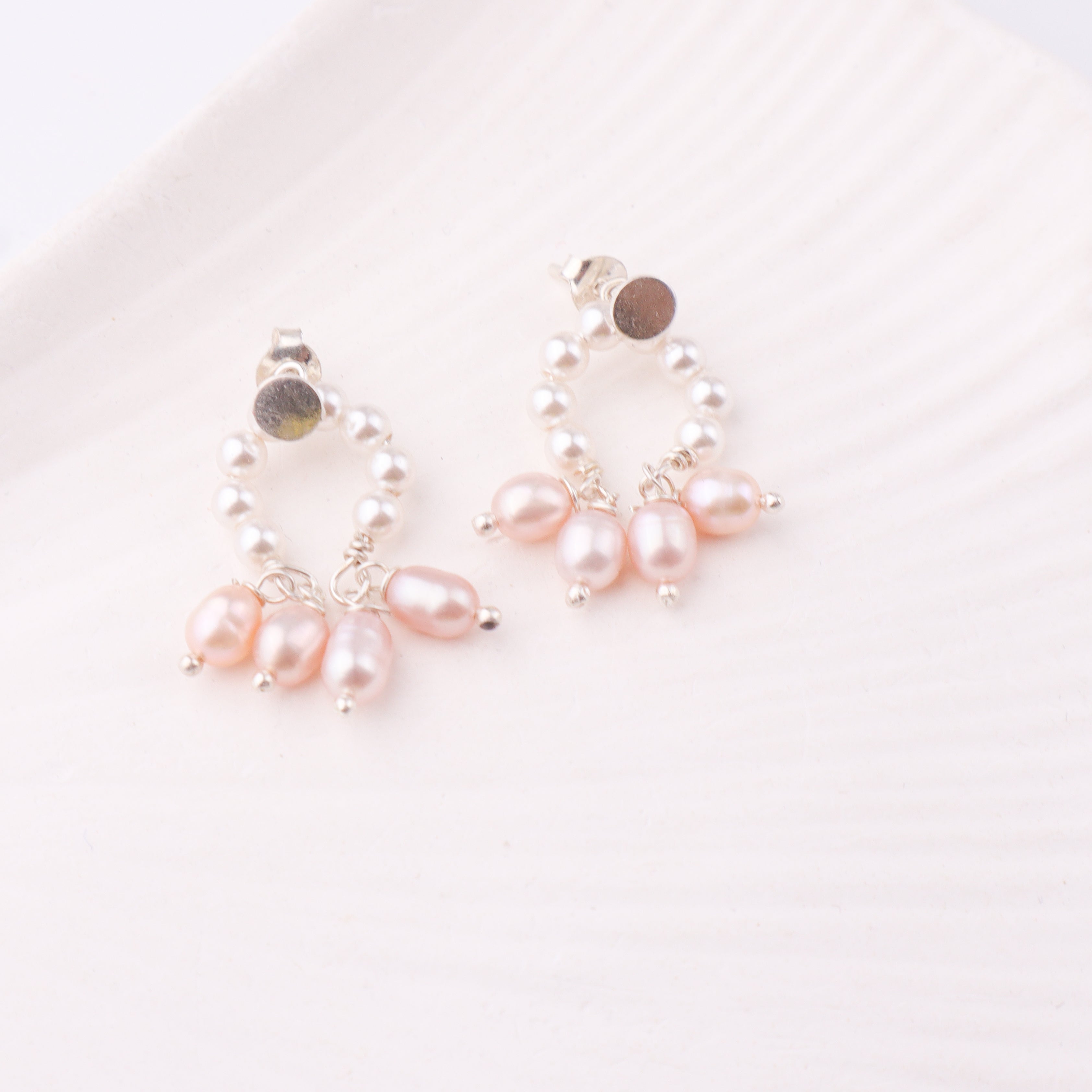 Silver earrings with pearl accents on white surface
