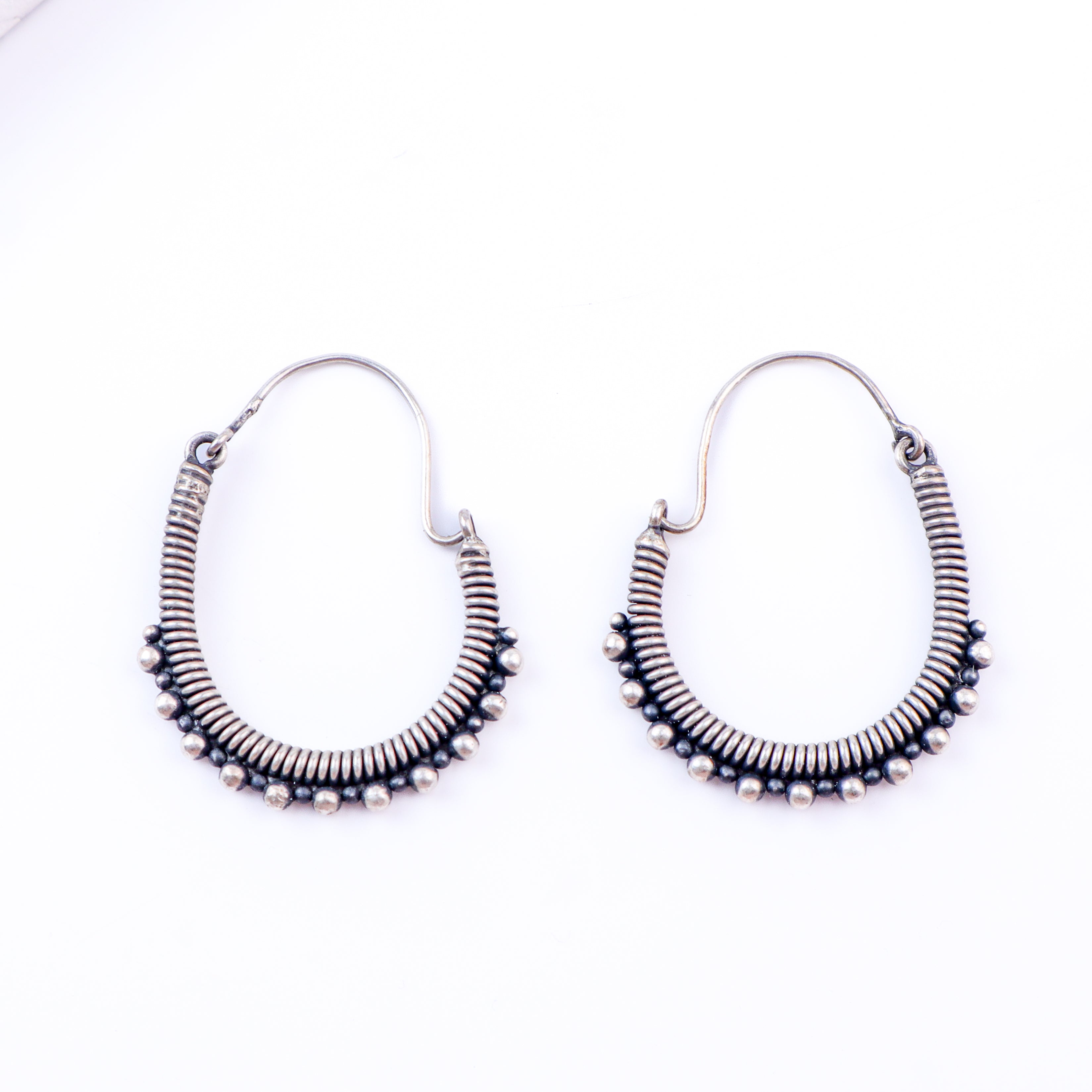 Flat-lay oxidized spring hoop earrings on neutral background
