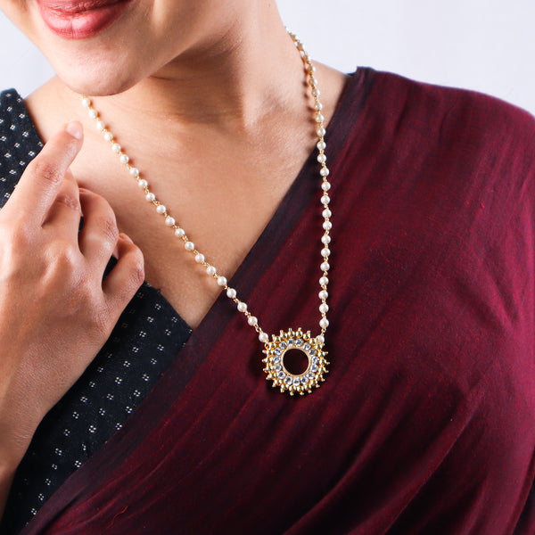 Model wearing pearl and gold necklace with pendant