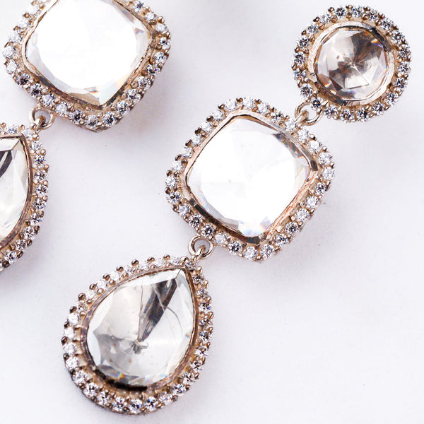 Close-up of silver earrings with large clear stones and surrounding smaller stones