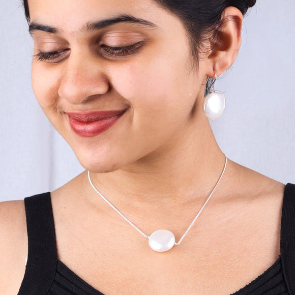 Model wearing pearl necklace and earrings in silver
