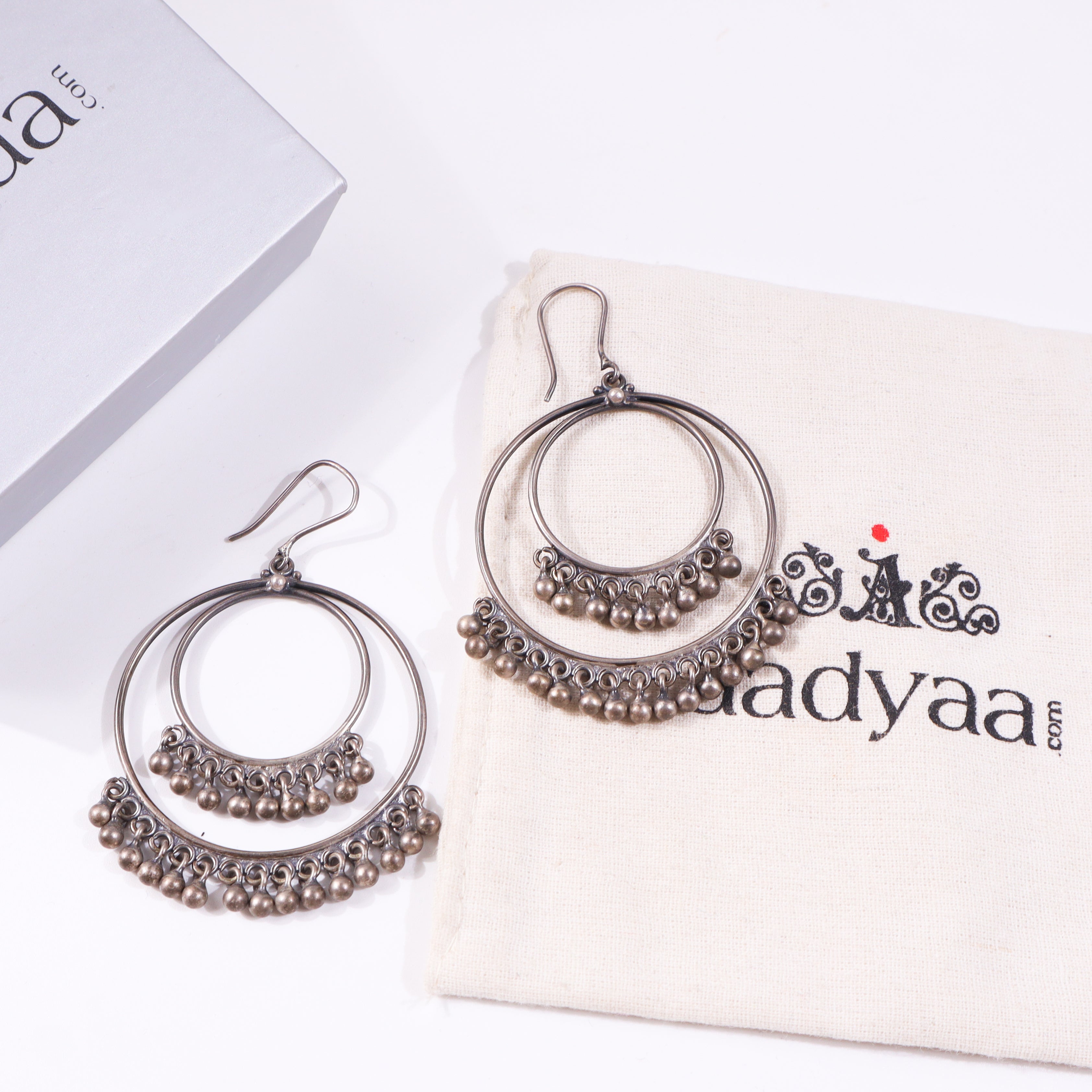 Silver hoop earrings with dangling beads on beige fabric