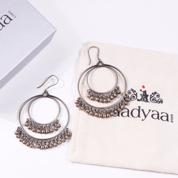Silver hoop earrings with dangling beads on beige fabric