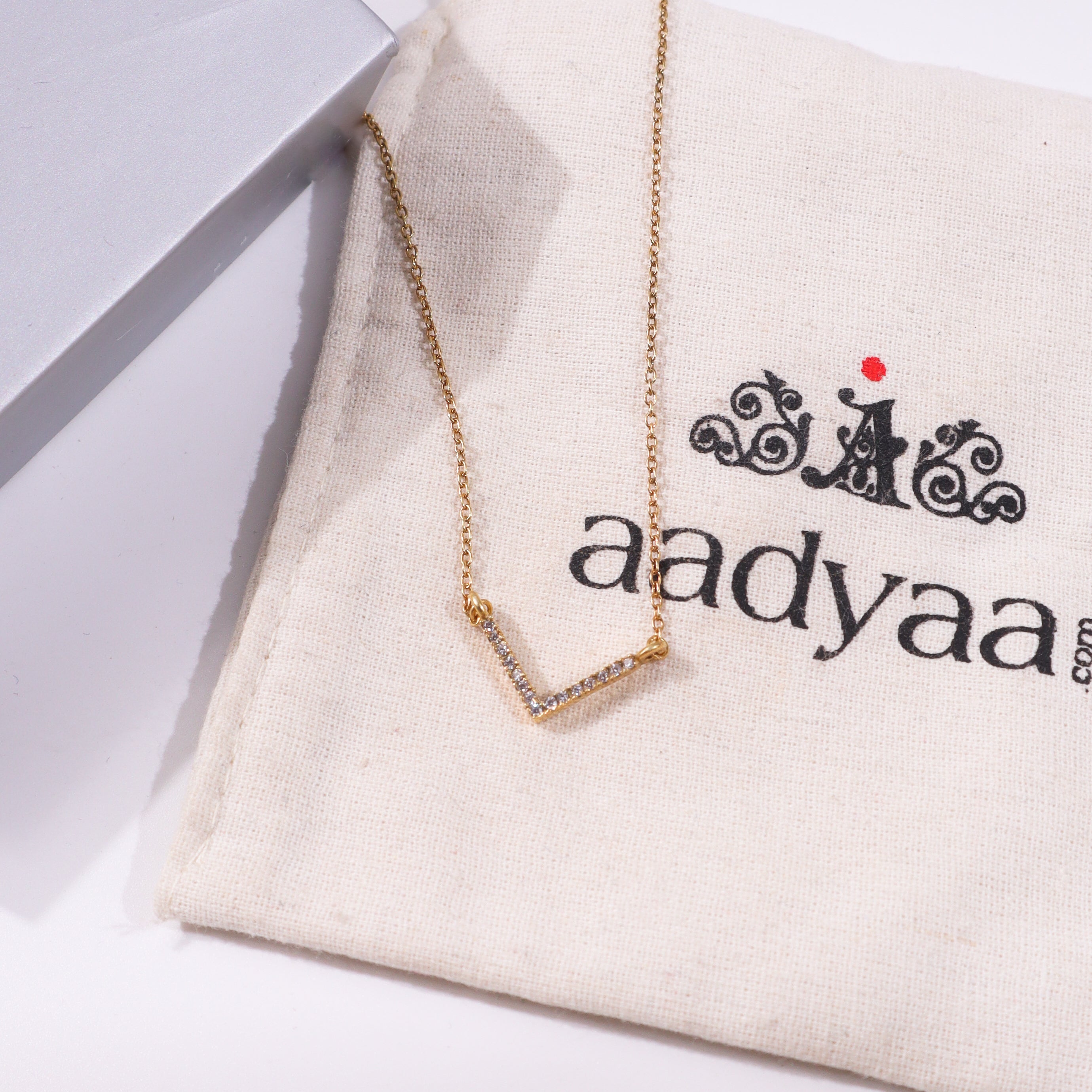 Gold V-shaped necklace with CZ stones on beige fabric
