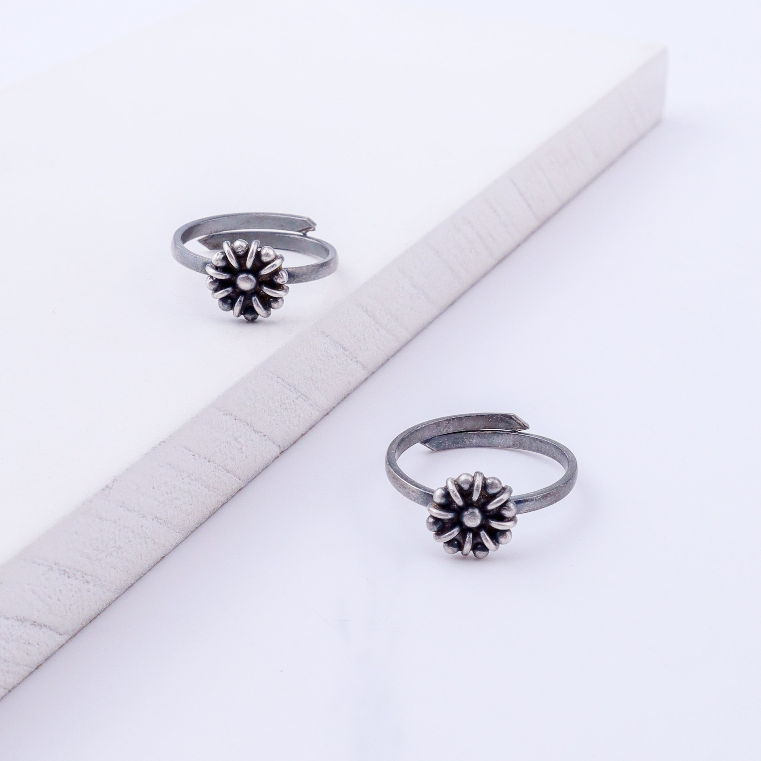 Angled view of tiny flower silver toe ring