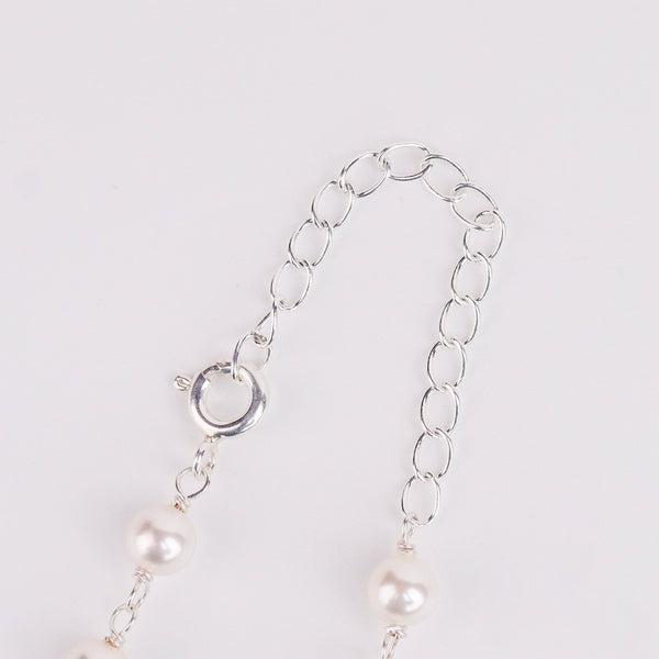 Flat-lay of pearl Ganthan necklace with semiprecious stones on silk fabric with soft natural light