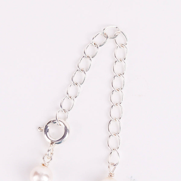 Flat-lay of pearl Ganthan necklace with semiprecious stones on silk fabric with soft natural light