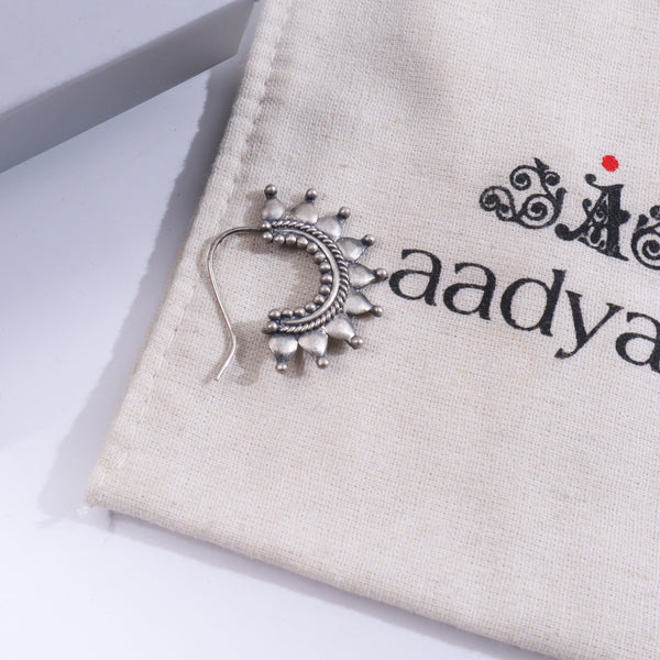 Sterling silver traditional nose pin with intricate design on beige fabric