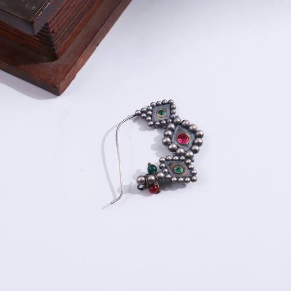 Silver Godavari Nath pierced nose pin with intricate design and green gemstone