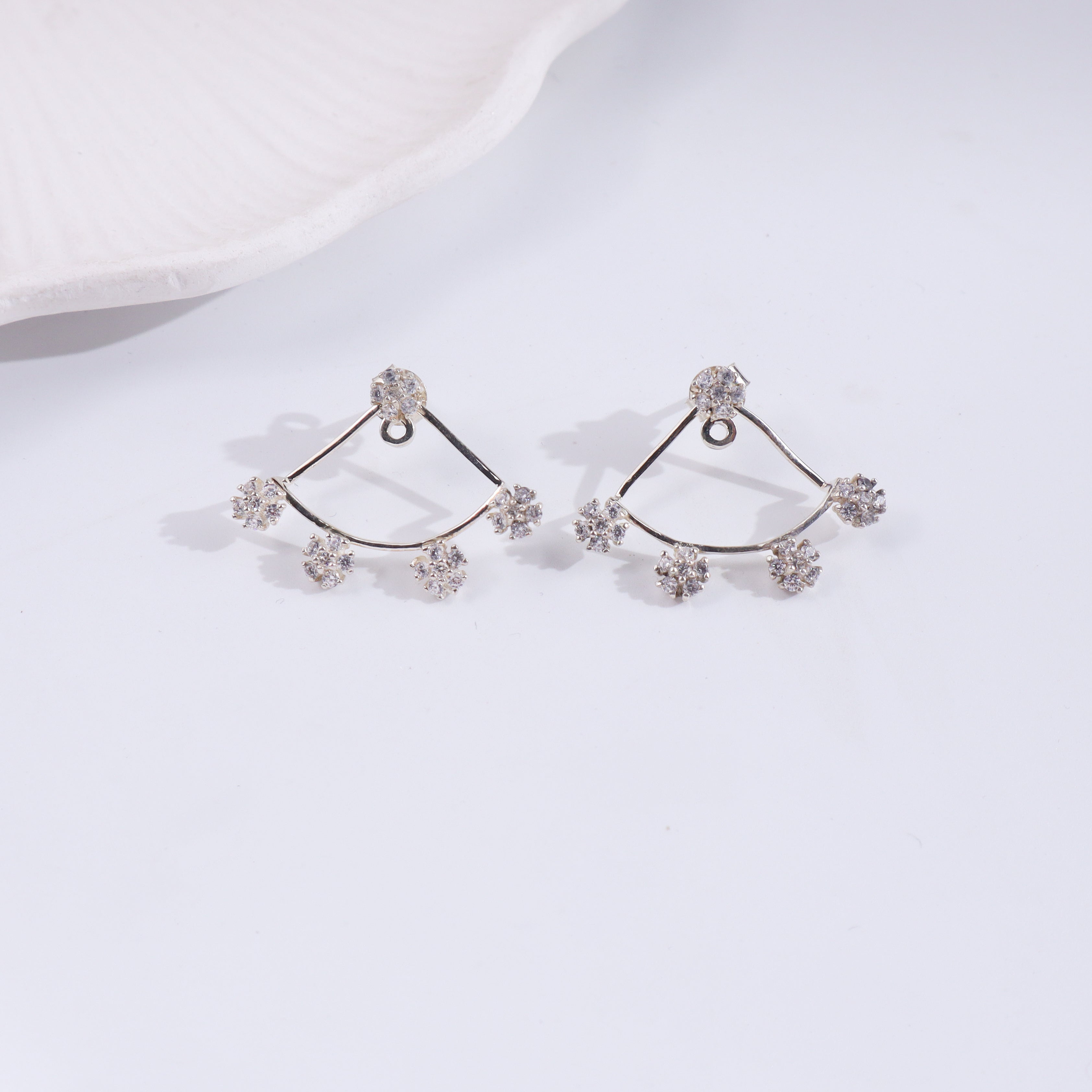 Silver flower CZ earrings on white fabric, detailed close-up