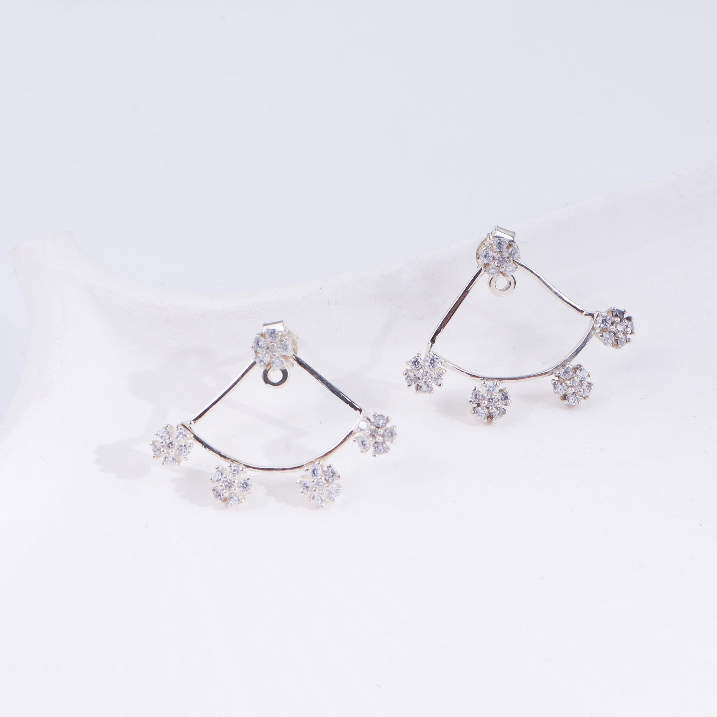 Silver flower CZ earrings on white background, side view