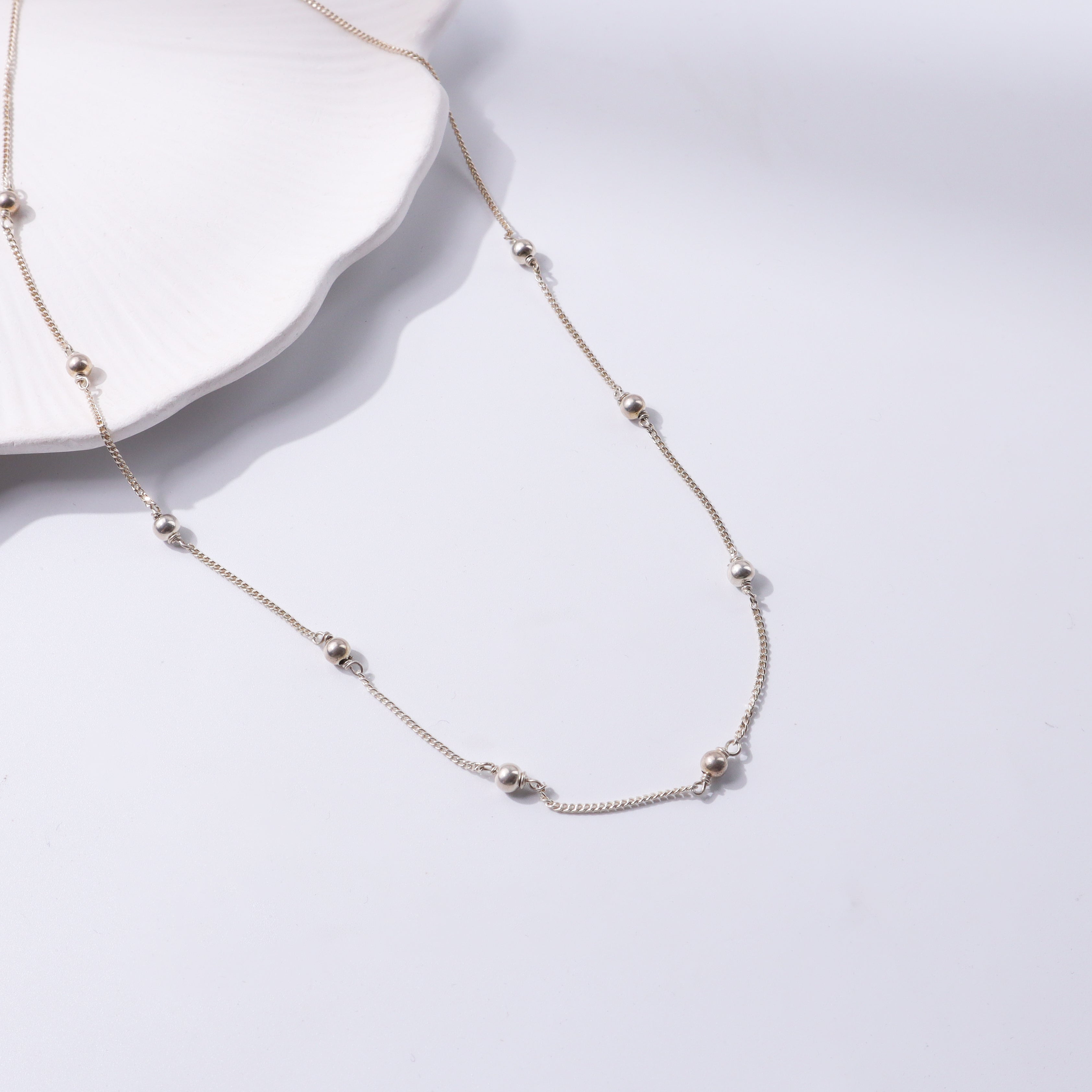 Close-up of silver beaded chain necklace on a white background