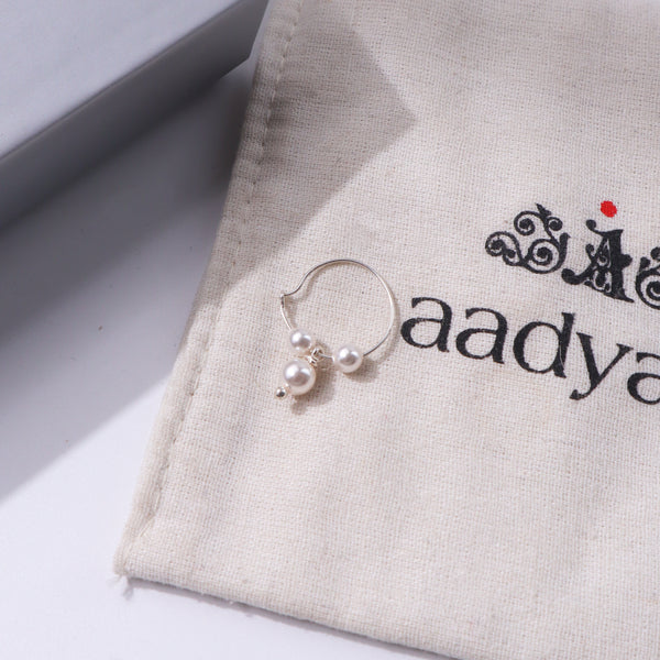 Pearl hoop earring with silver accents on beige fabric