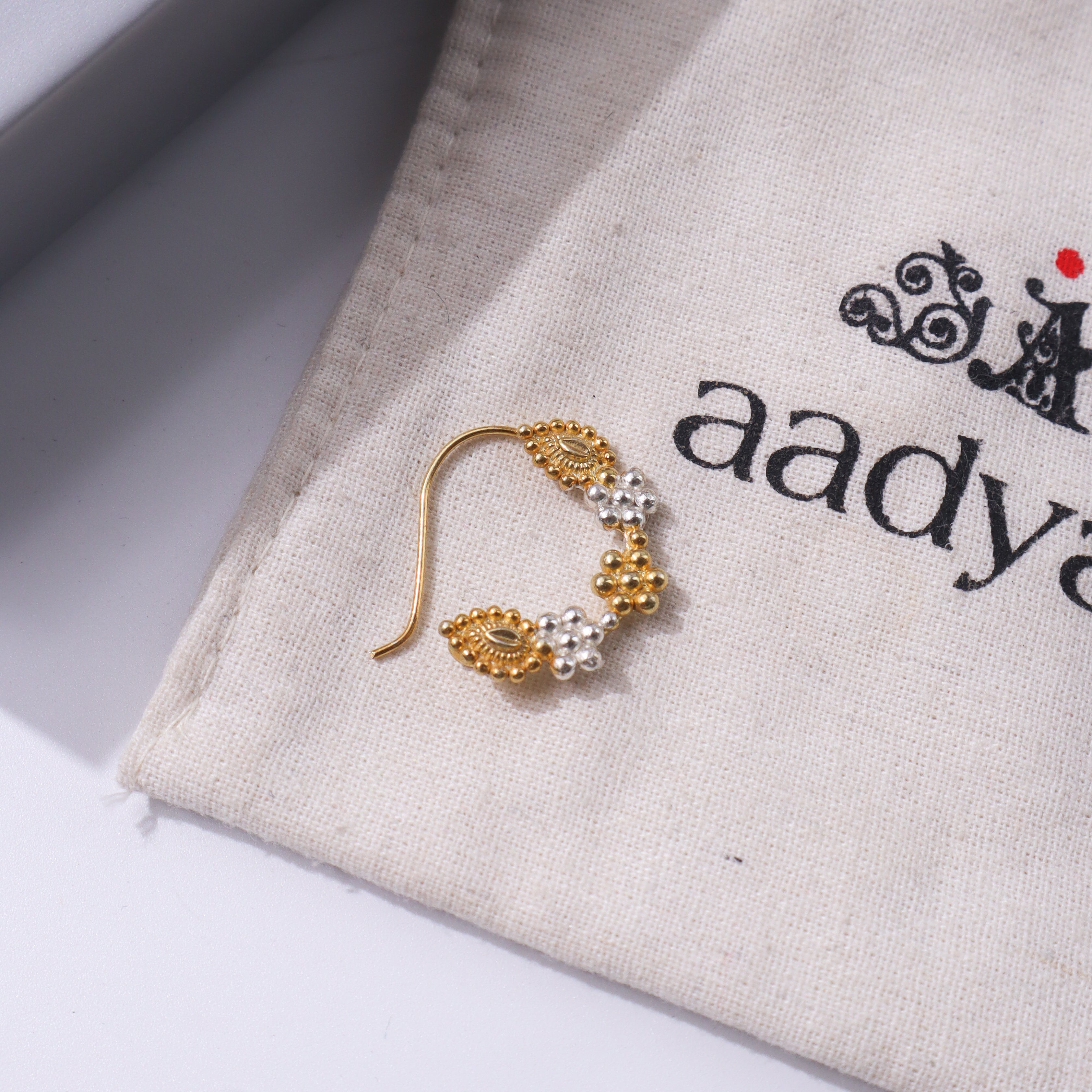 Gold nose ring with pearl embellishments on beige fabric