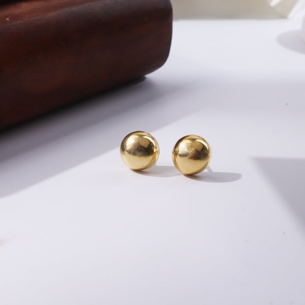 Gold spherical earrings on white background