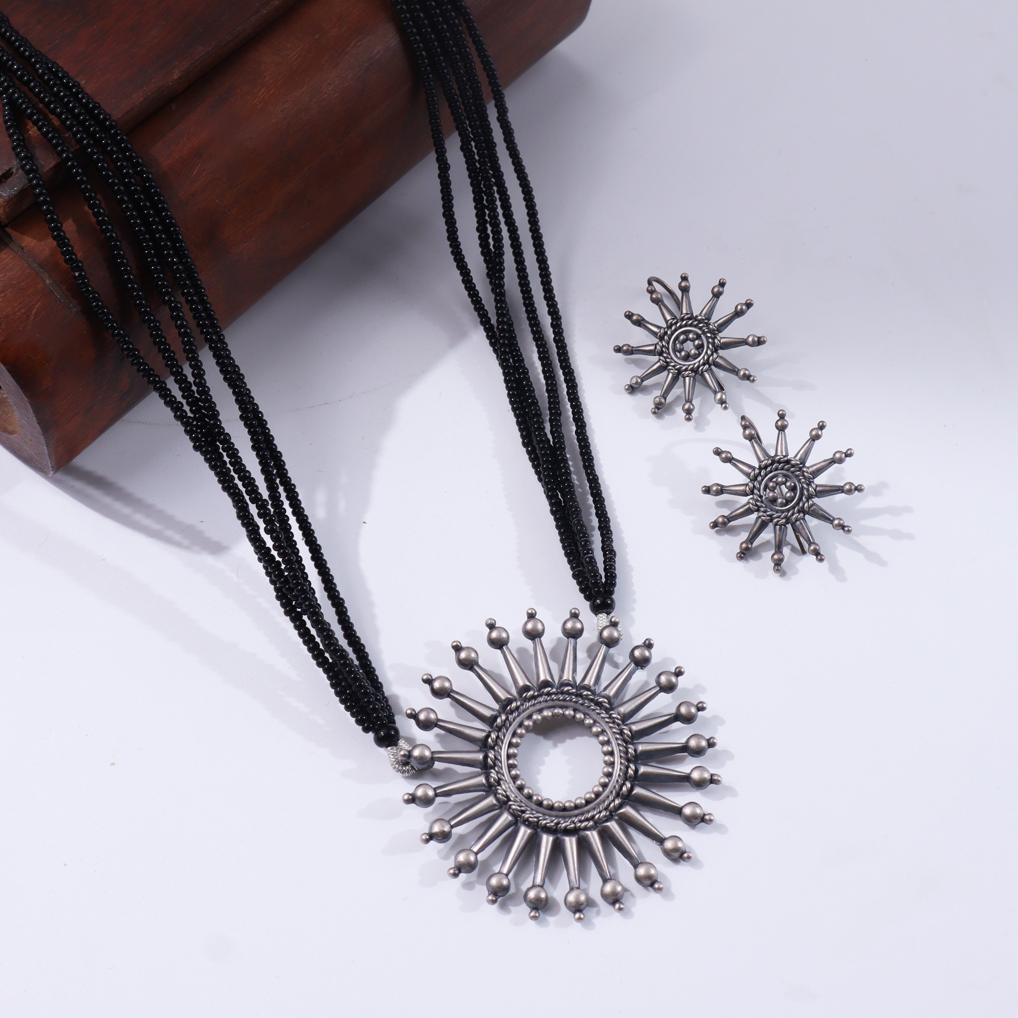 Black beaded silver necklace with sun-shaped pendant