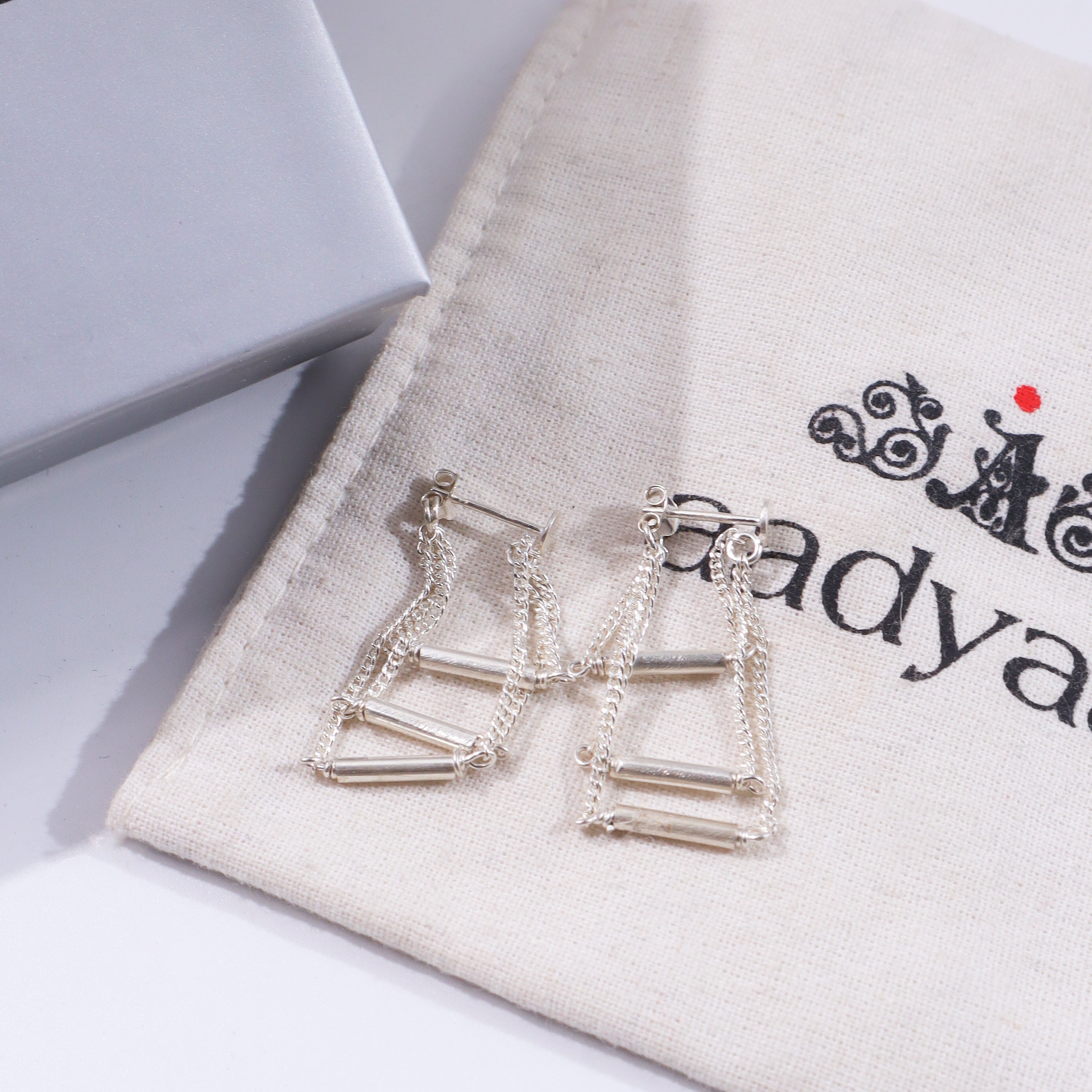 Silver layered chain earrings on beige fabric