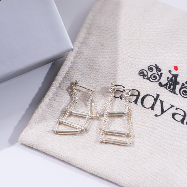 Silver layered chain earrings on beige fabric