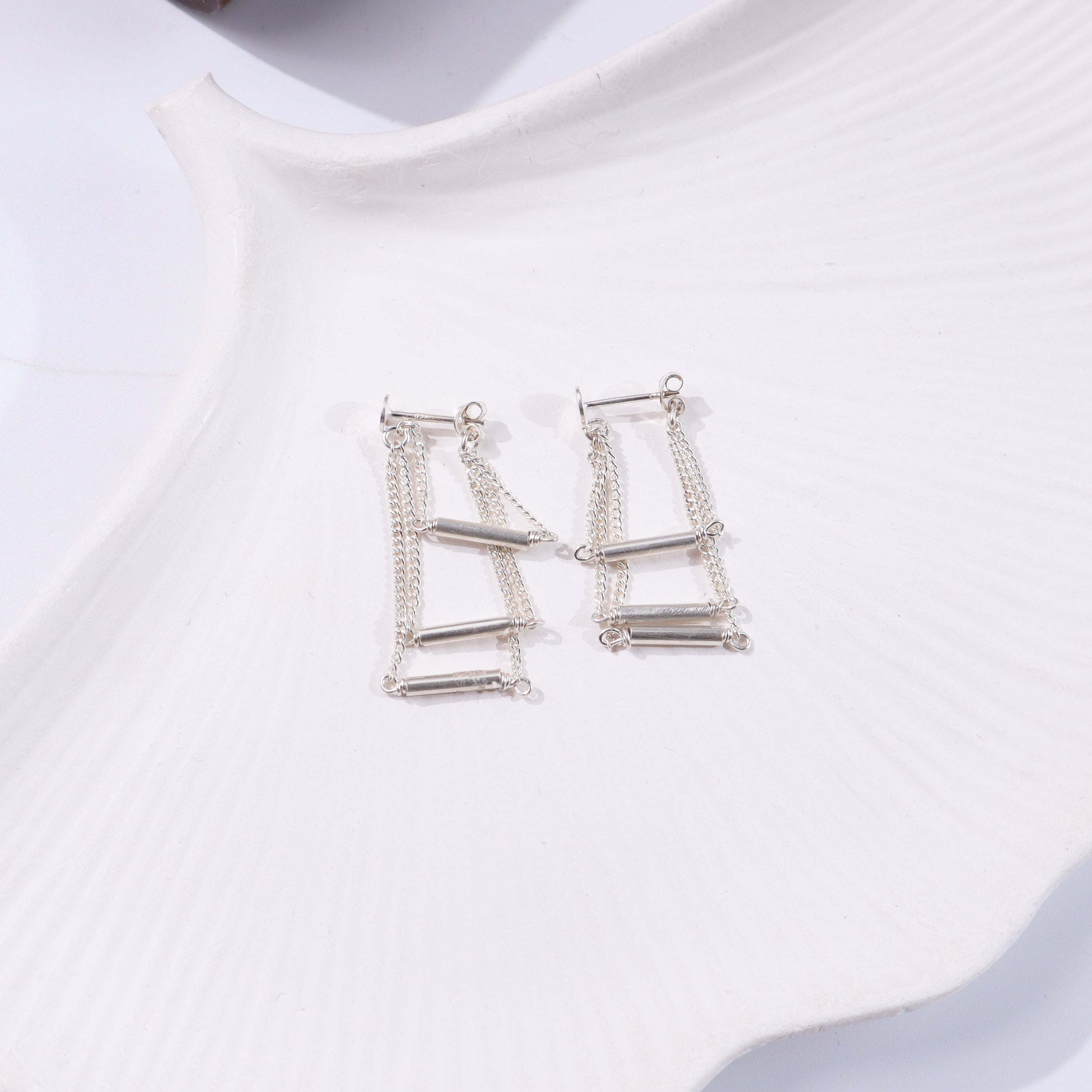 Silver layered chain earrings on white display