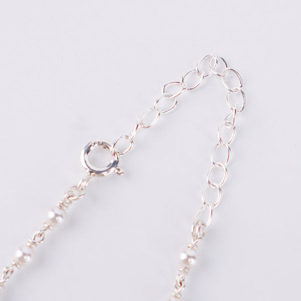 Flat-lay of 3mm pearl Gantan necklace on silk fabric with soft natural light