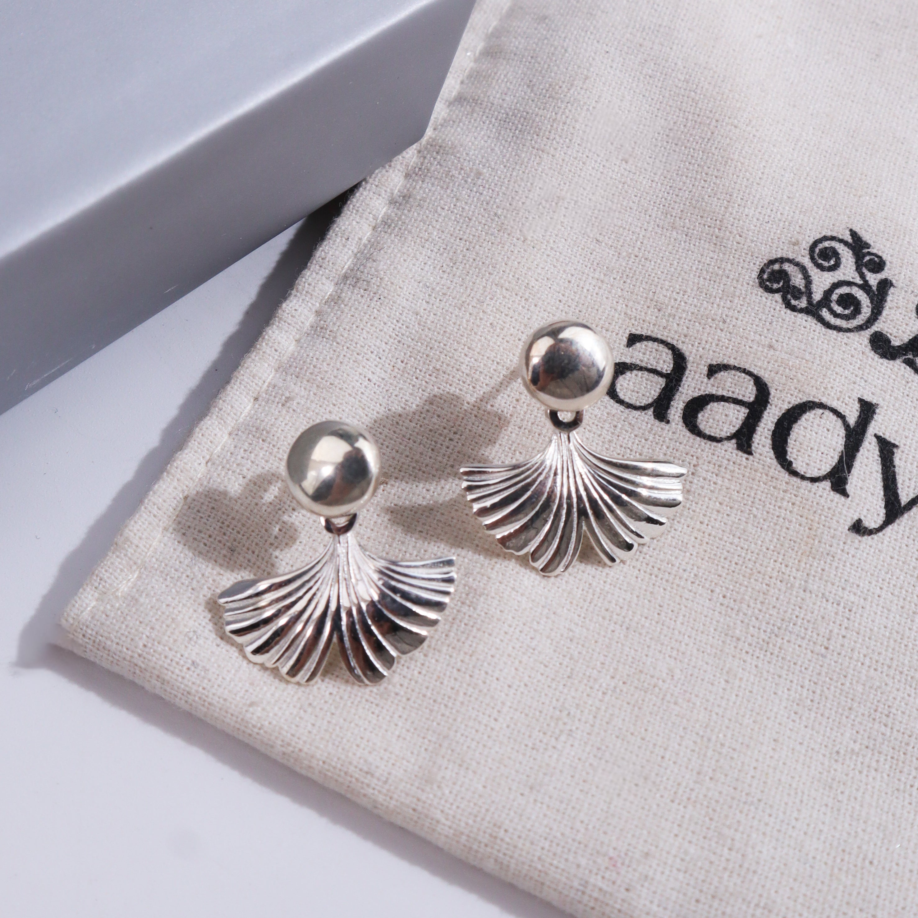 Silver earrings with ginkgo leaf design on jewelry display