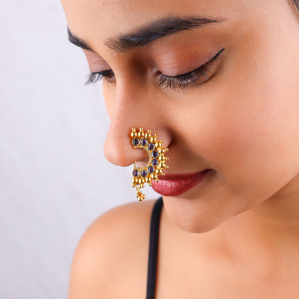 Close-up of gold nose pin with purple stones